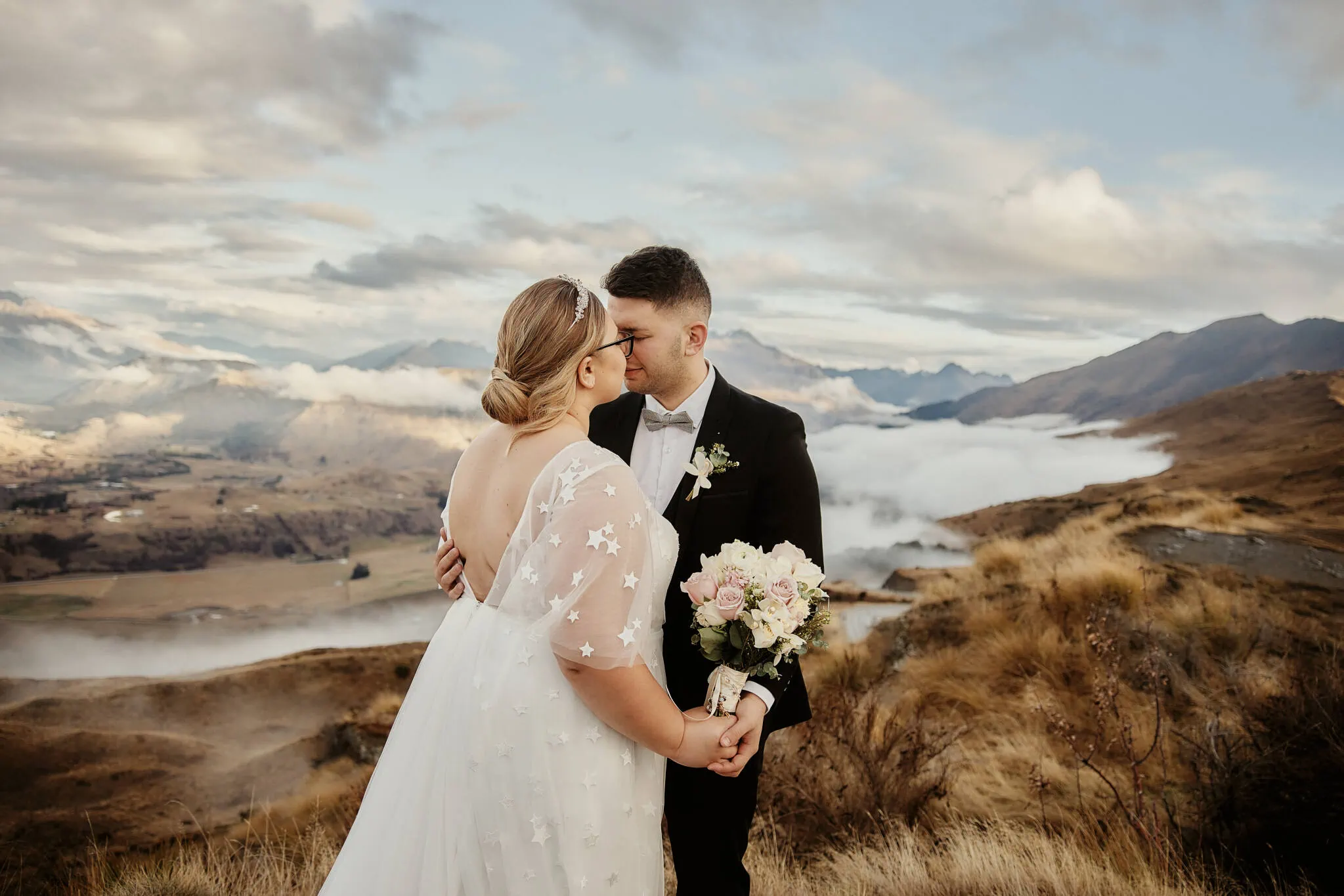 Queenstown New Zealand Elopement Wedding Photographer - Caitiann and Kiyo's elopement wedding at Coronet Peak, New Zealand, featuring a romantic kiss on top of a mountain.