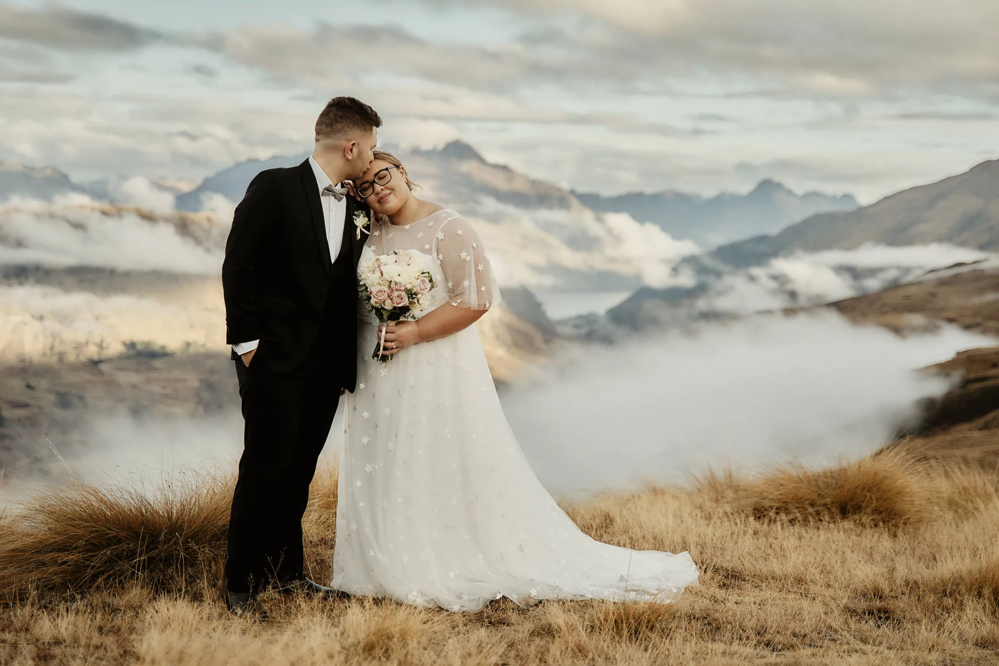 Queenstown New Zealand Elopement Wedding Photographer - Caitiann and Kiyo's Coronet Peak Elopement Wedding captures a bride and groom kissing on top of a mountain in New Zealand.
