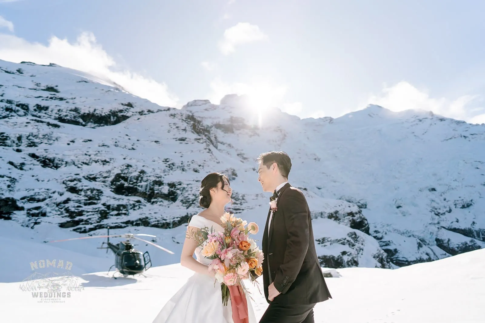Queenstown New Zealand Elopement Wedding Photographer - Bo and Junyi's heli pre wedding shoot captures them standing in front of a majestic snow-covered mountain, after making four exhilarating landings.