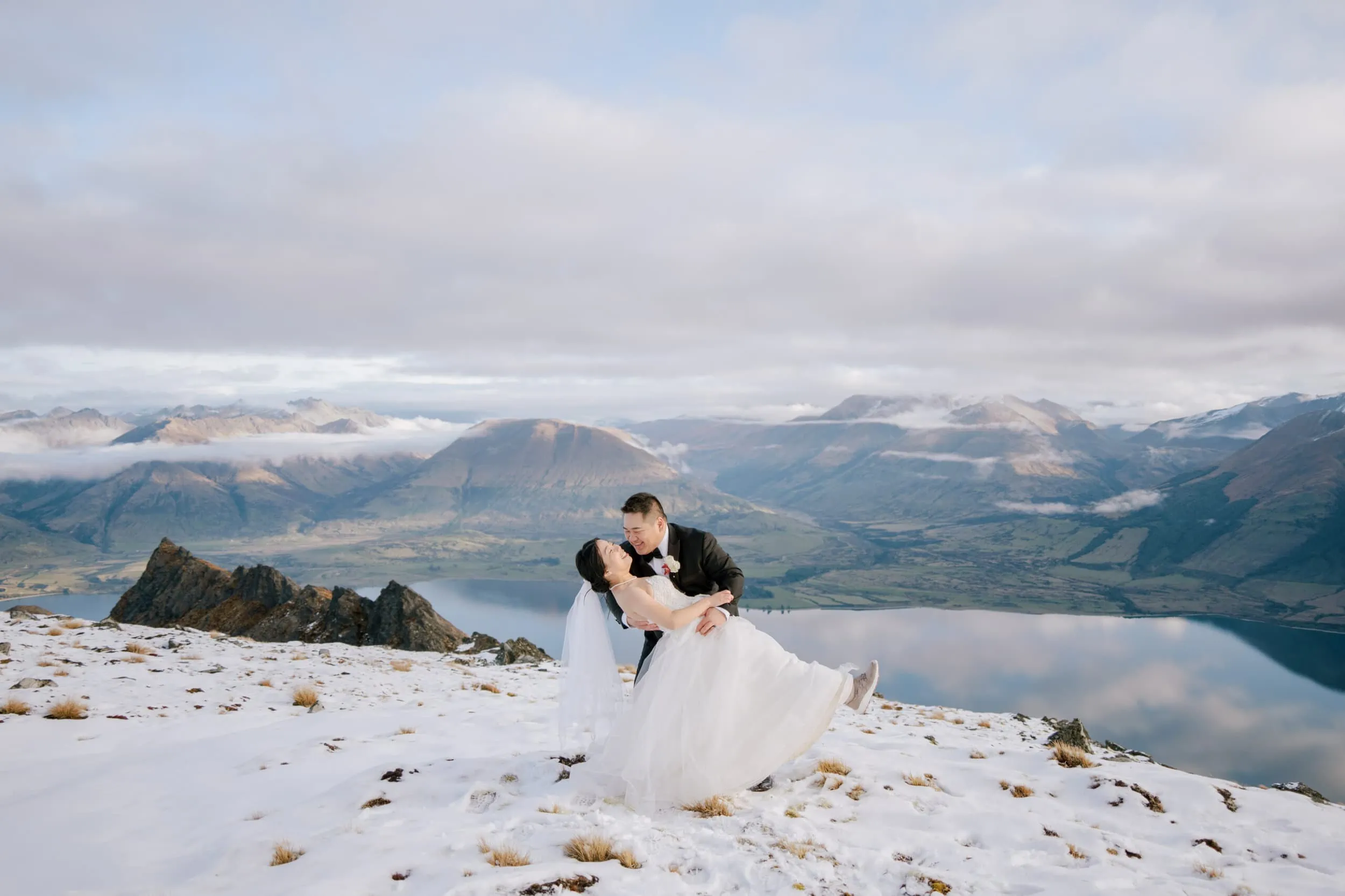 Queenstown New Zealand Elopement Wedding Photographer - Bride and groom enjoying a Lam and Wendy's Kamana Lakehouse Wedding on top of a snow covered mountain in queenstown, new zealand.