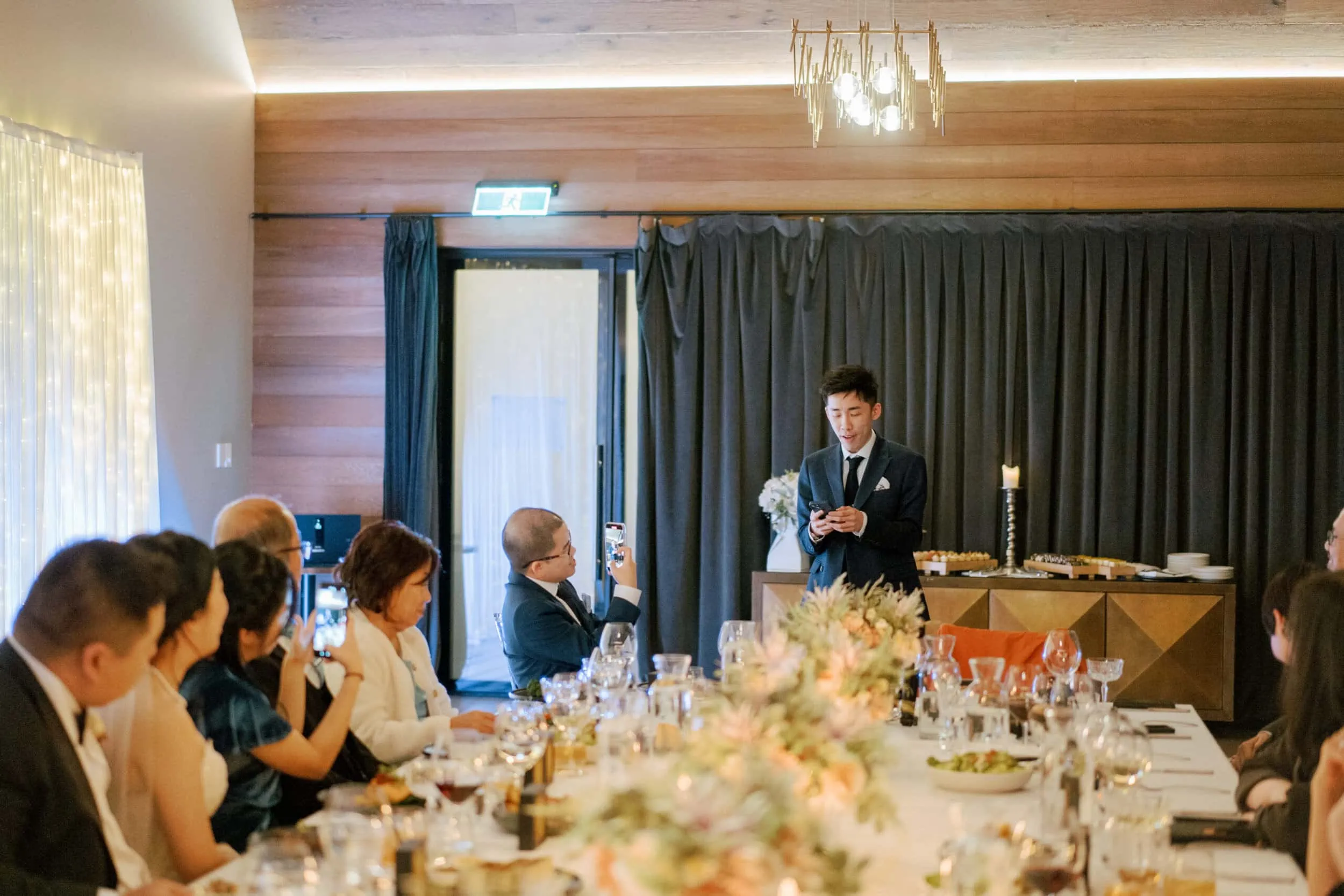 Queenstown New Zealand Elopement Wedding Photographer - A man giving a speech at Lam and Wendy's wedding reception at Kamana Lakehouse.