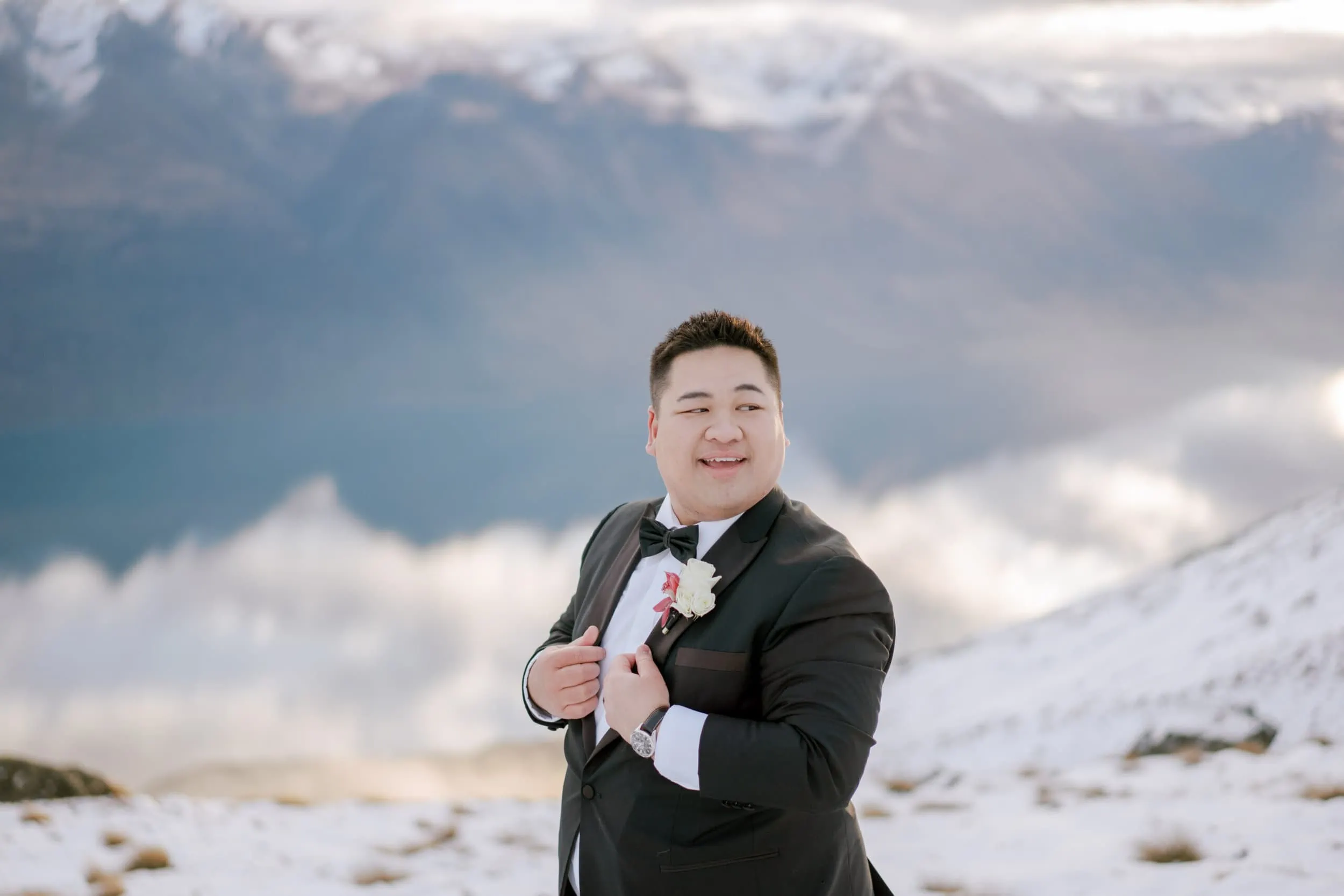 Queenstown New Zealand Elopement Wedding Photographer - A man in a tuxedo enjoying a Lam and Wendy's Kamana Lakehouse Wedding on top of a snowy mountain.