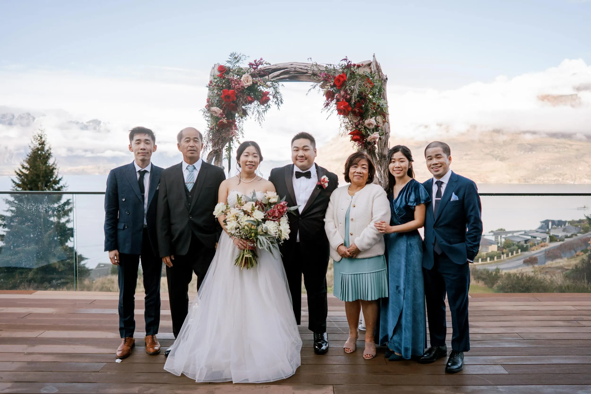 Queenstown New Zealand Elopement Wedding Photographer - Lam and Wendy's wedding party posing for a photo on a deck overlooking Lake Wanaka at Kamana Lakehouse.