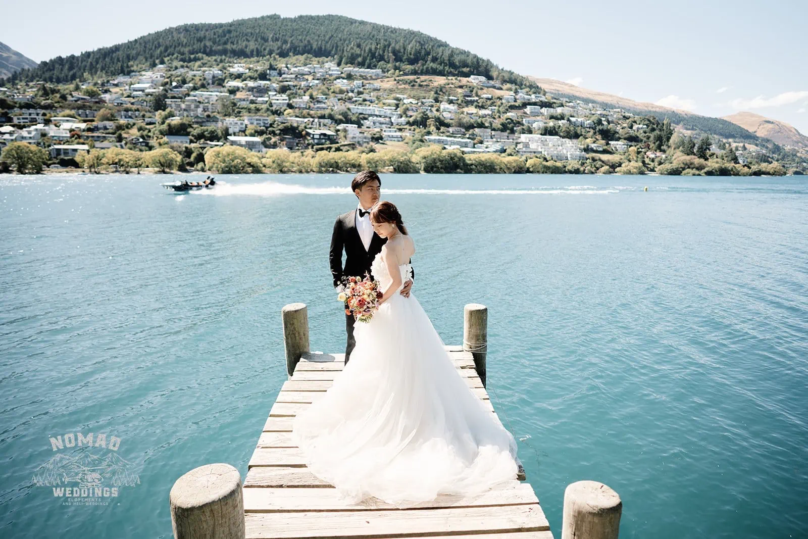 Queenstown New Zealand Elopement Wedding Photographer - A bride and groom standing on a dock in front of a lake during summer.