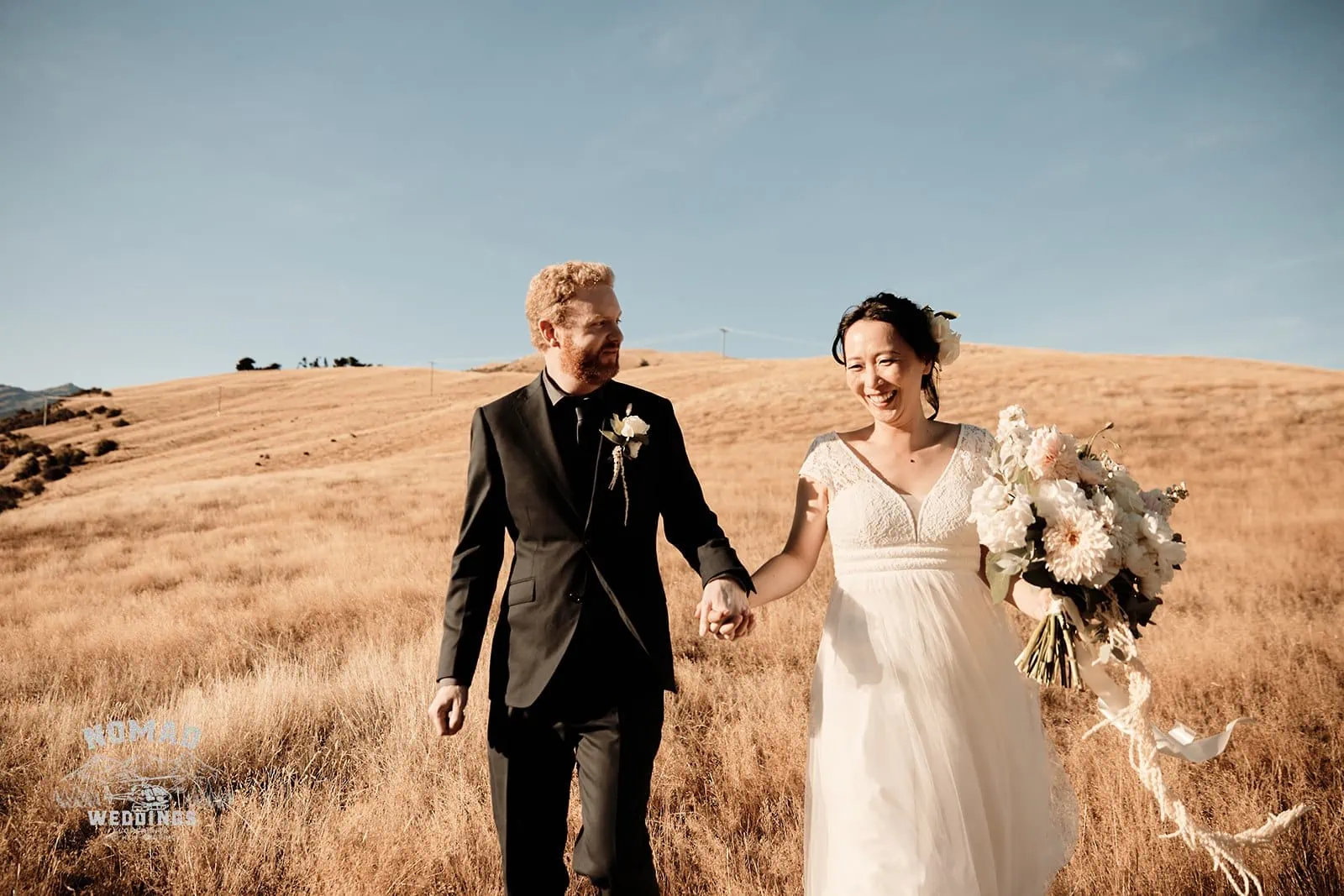 Queenstown New Zealand Elopement Wedding Photographer - A couple walking through a grassy field in Queenstown during the summer.