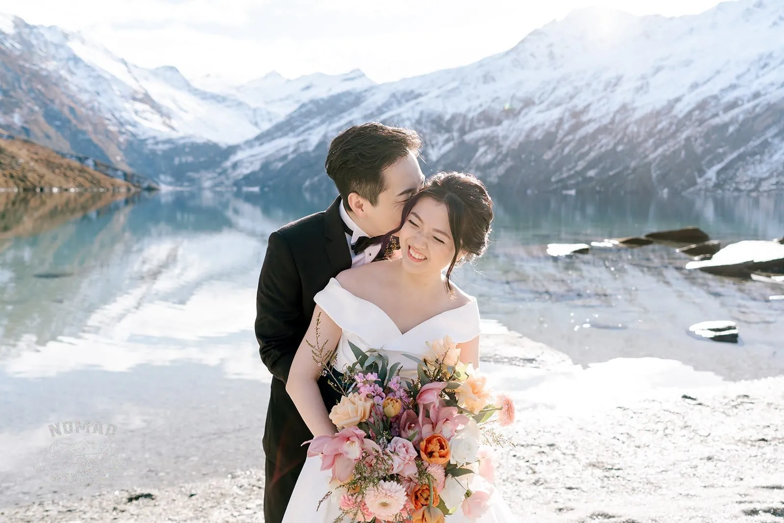 Queenstown New Zealand Elopement Wedding Photographer - Bo and Junyi, a bride and groom, share an intimate embrace during their Heli Pre Wedding Shoot with 4 Landings by a lake in New Zealand.