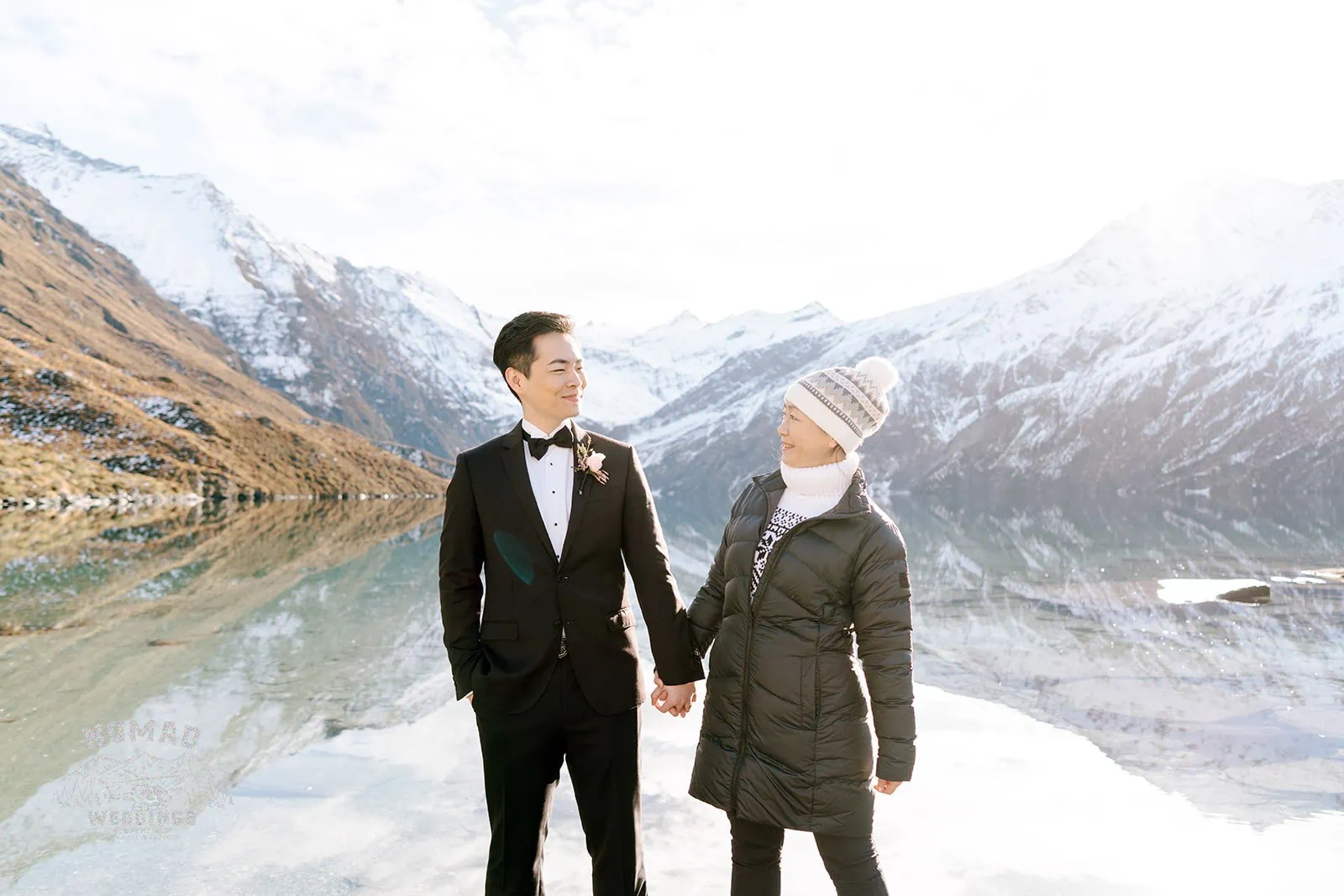 Queenstown New Zealand Elopement Wedding Photographer - Bo and Junyi's heli pre wedding shoot with 4 landings captures a couple holding hands in front of a lake in New Zealand.
