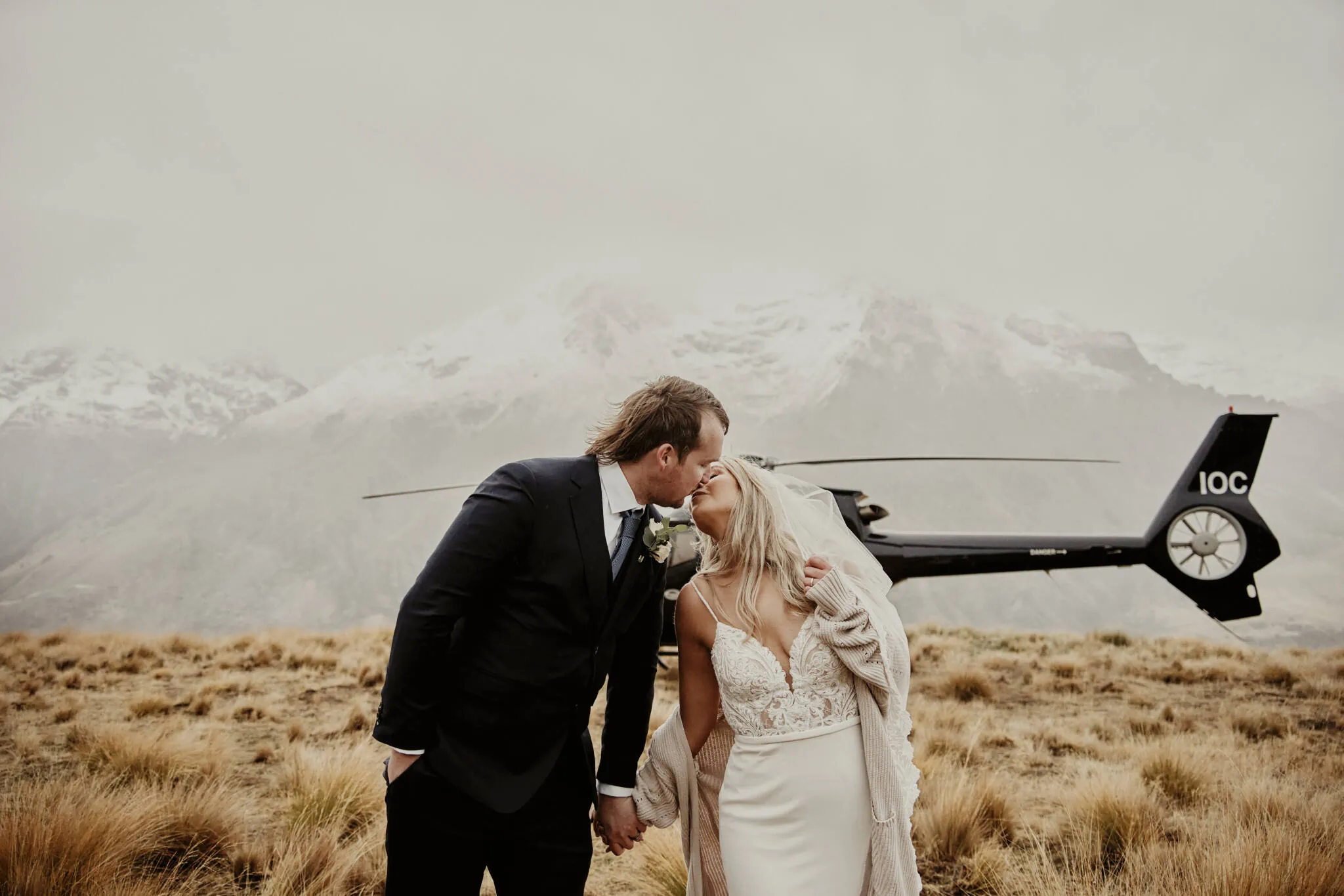 Queenstown New Zealand Elopement Wedding Photographer - Rebecca and Dylan share an enchanting kiss in front of a helicopter during their Moke Lake elopement wedding.