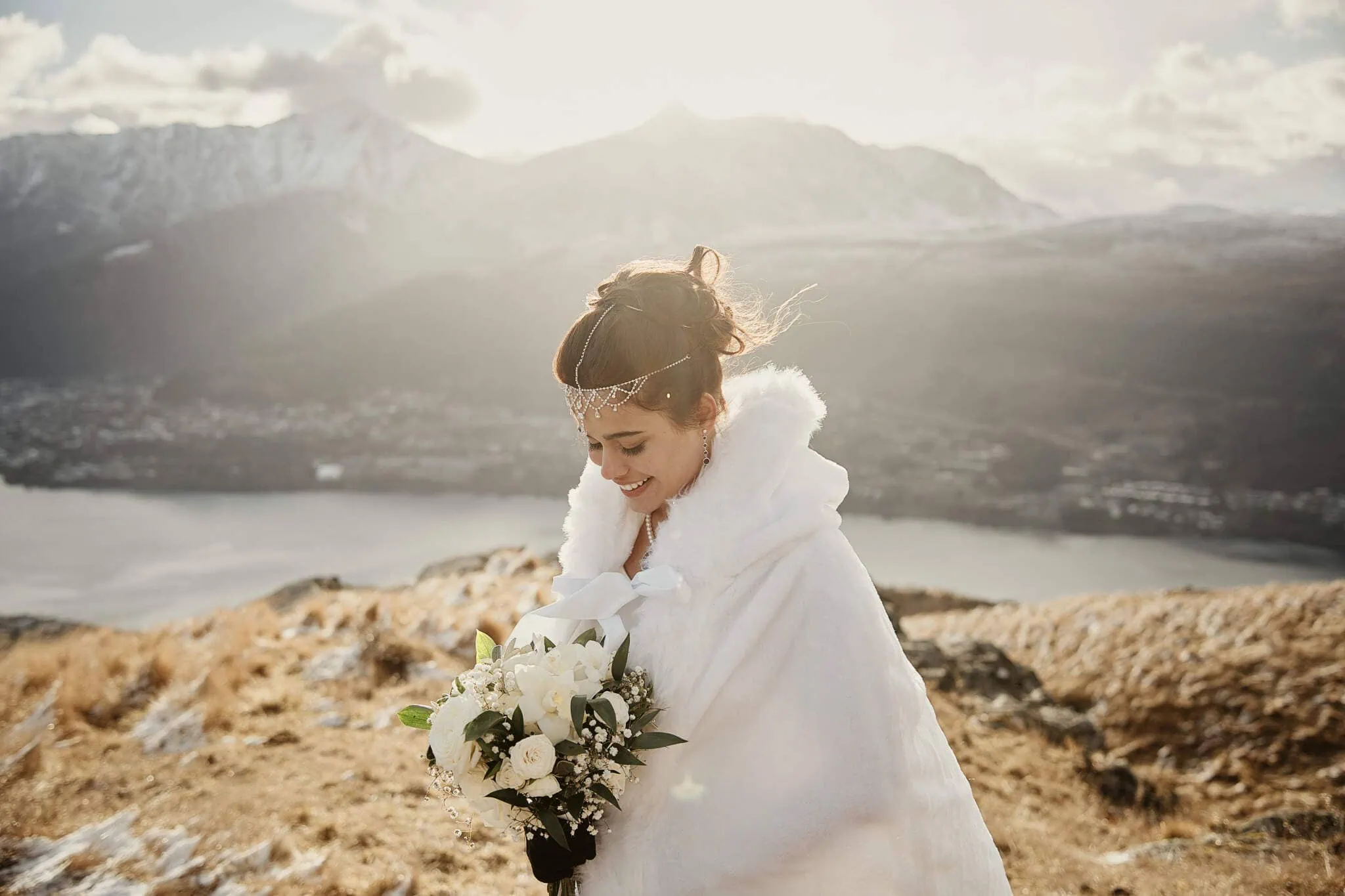 Queenstown New Zealand Elopement Wedding Photographer - A bride wearing a white cloak standing on top of a hill overlooking Lake Wanaka during the Queenstown Islamic wedding of Wasim and Yumn.
