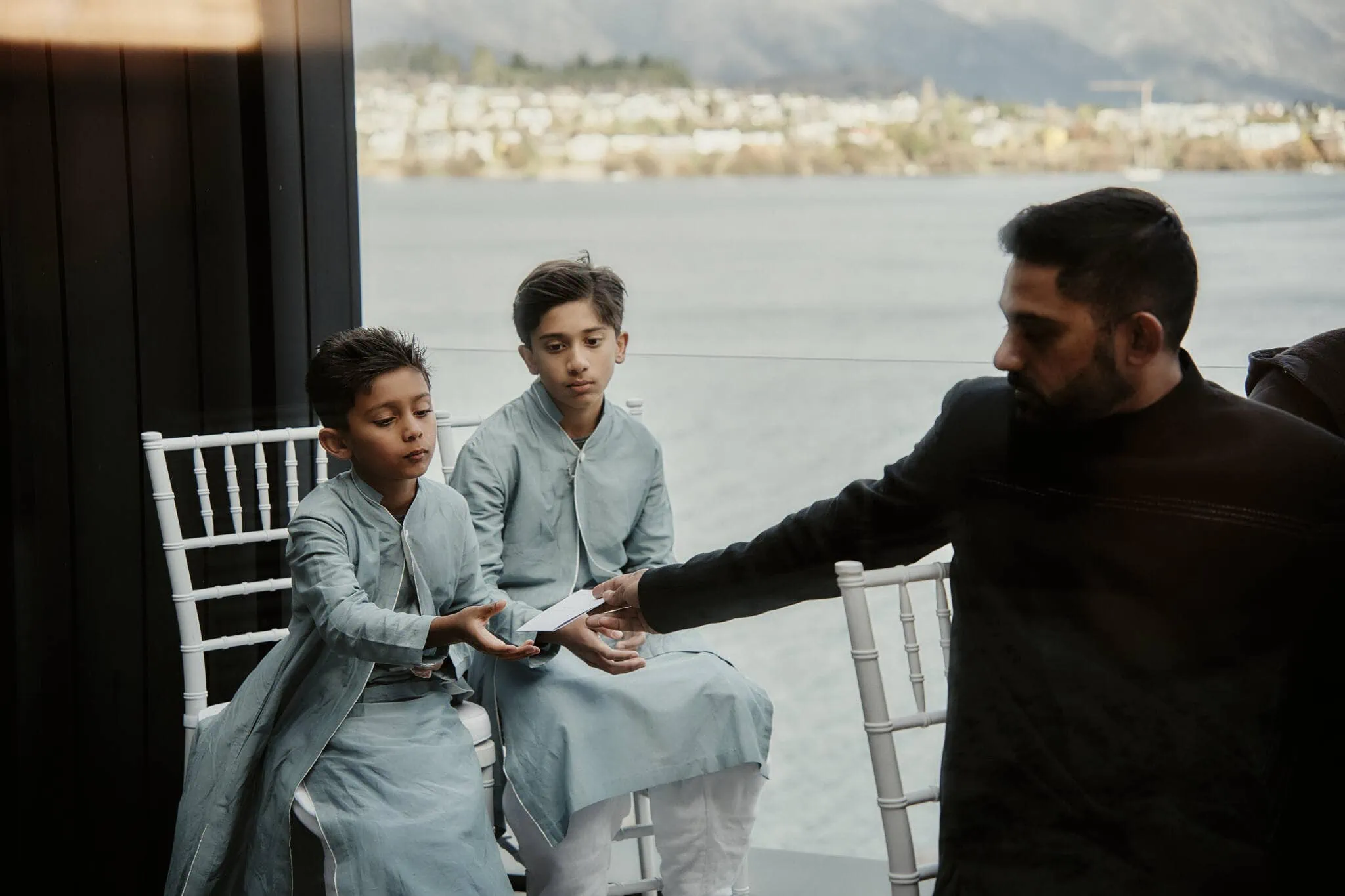 Queenstown New Zealand Elopement Wedding Photographer - A man in a blue kurta handing a boy a gift at Wasim and Yumn's Queenstown Islamic wedding.