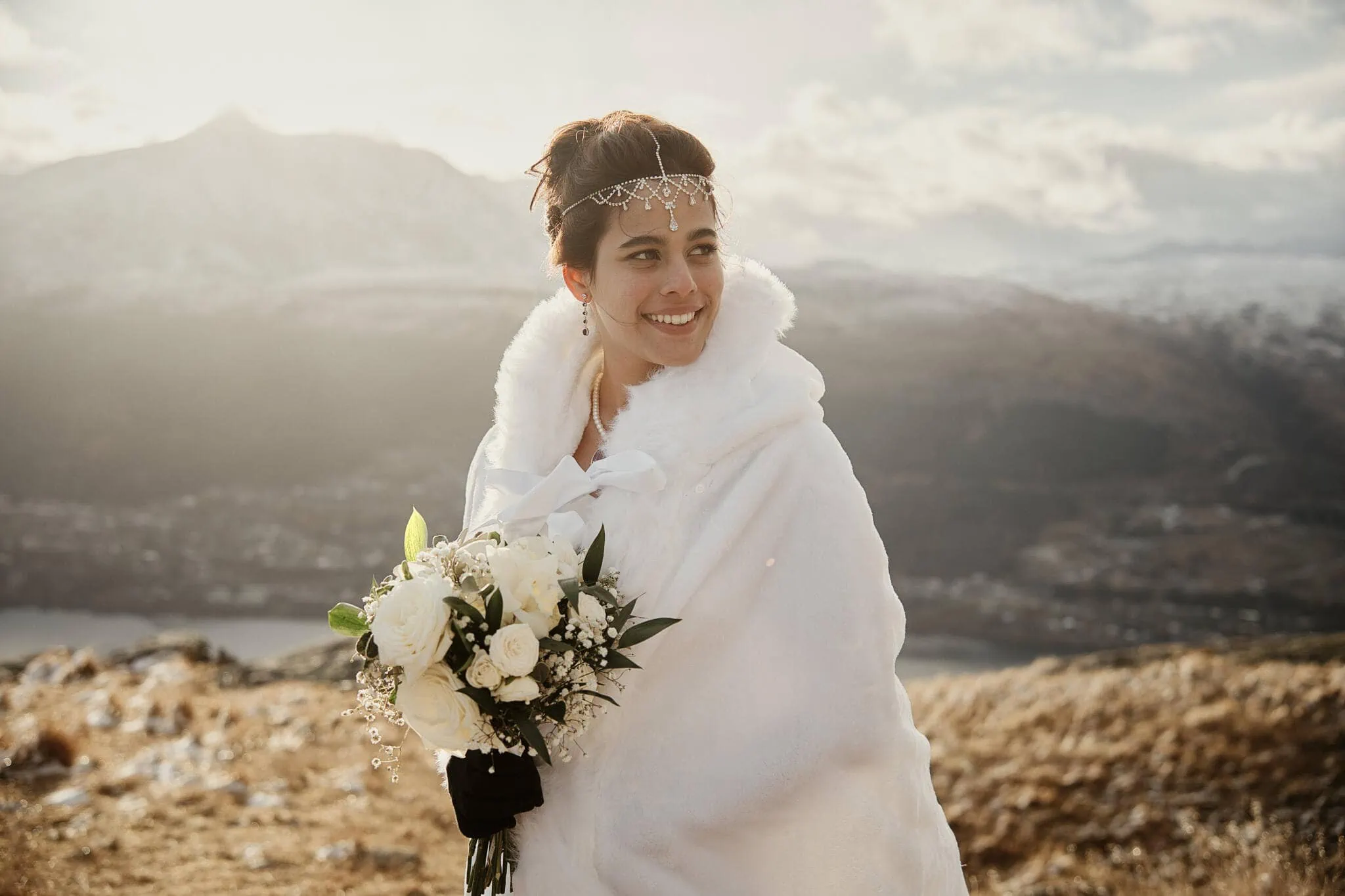 Queenstown New Zealand Elopement Wedding Photographer - A bride, Yumn, is standing on top of a hill in Queenstown with mountains in the background.