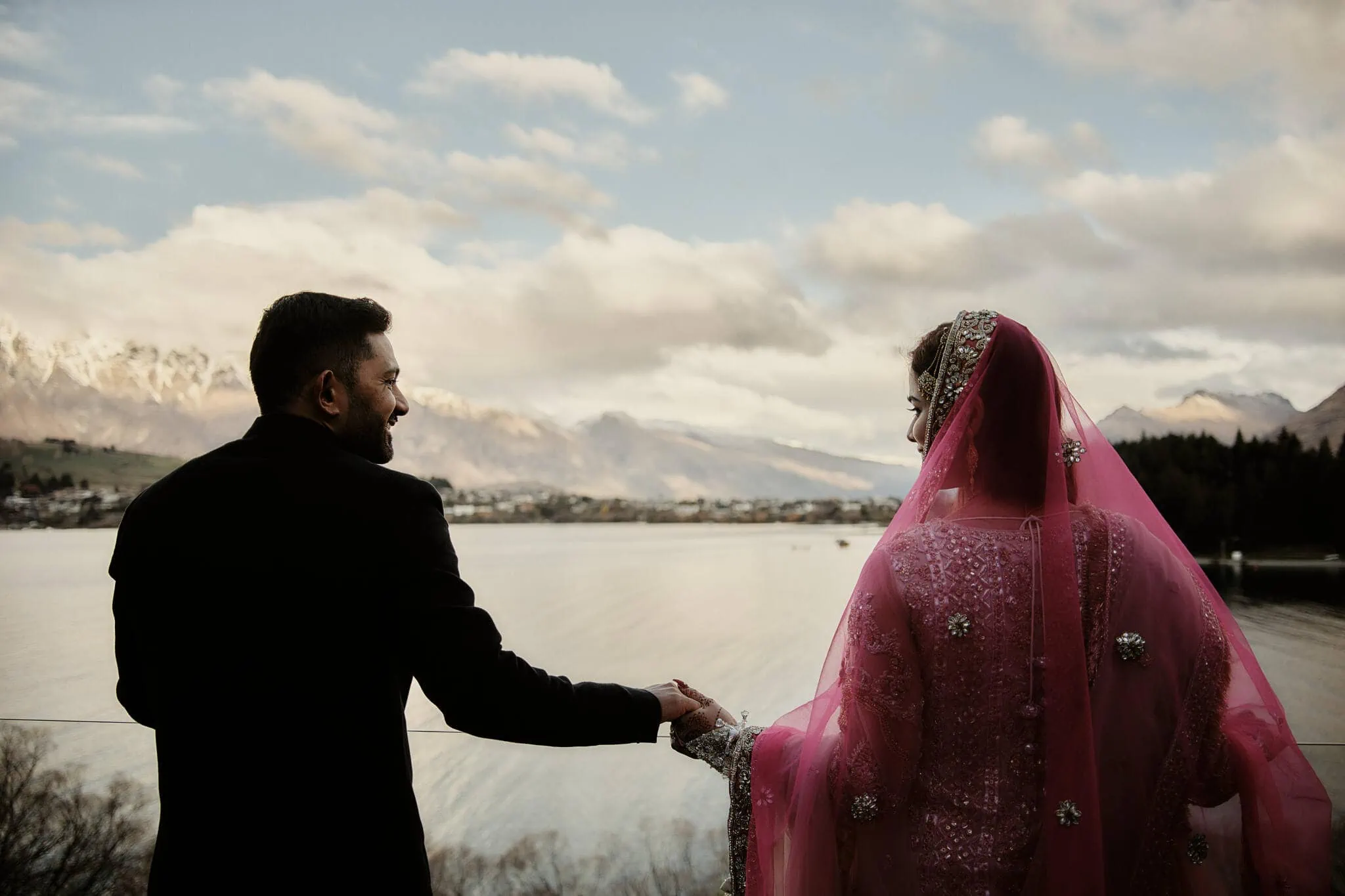 Queenstown New Zealand Elopement Wedding Photographer - Wasim and Yumn's Queenstown Islamic Wedding: A bride and groom holding hands in front of a lake.