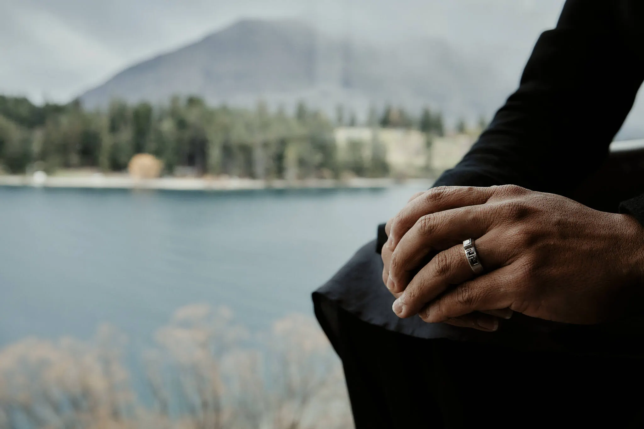 Queenstown New Zealand Elopement Wedding Photographer - A man's hand holding a ring near a lake at the Queenstown Islamic Wedding ceremony.