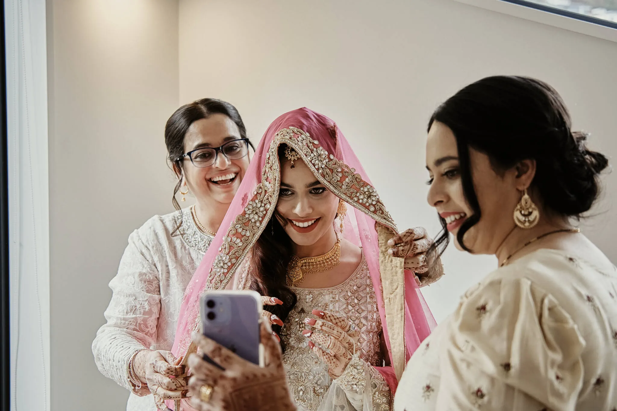Queenstown New Zealand Elopement Wedding Photographer - Wasim and Yumn's Queenstown Islamic Wedding - A bride and bridesmaids are taking a selfie in front of a mirror.