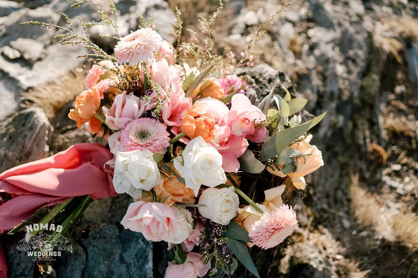 Queenstown New Zealand Elopement Wedding Photographer - Bo and Junyi's Heli Pre Wedding Shoot included a bouquet of pink and peach flowers on a rock.