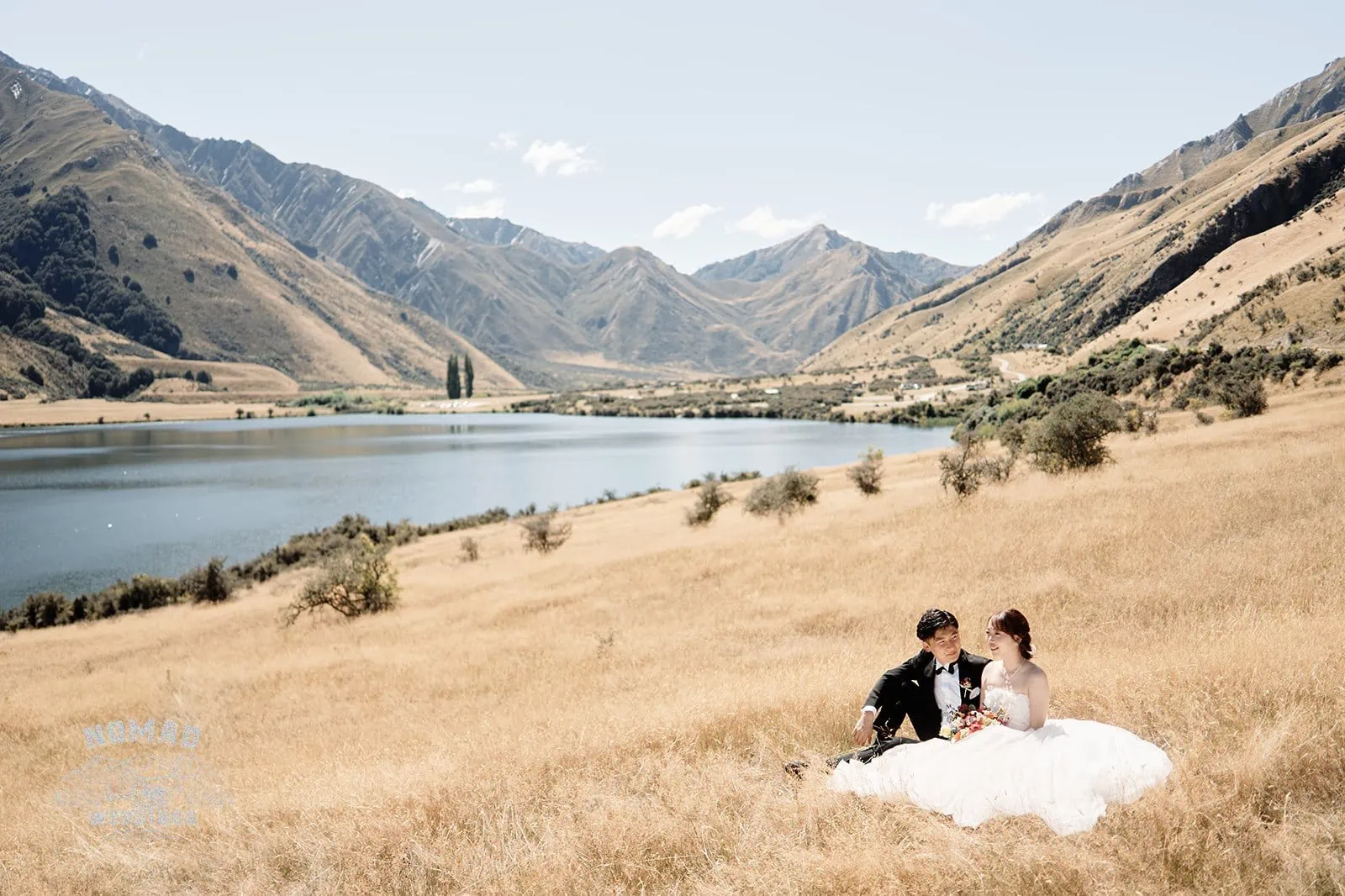Queenstown New Zealand Elopement Wedding Photographer - A bride and groom enjoying a summer picnic on a grassy hill in Queenstown.