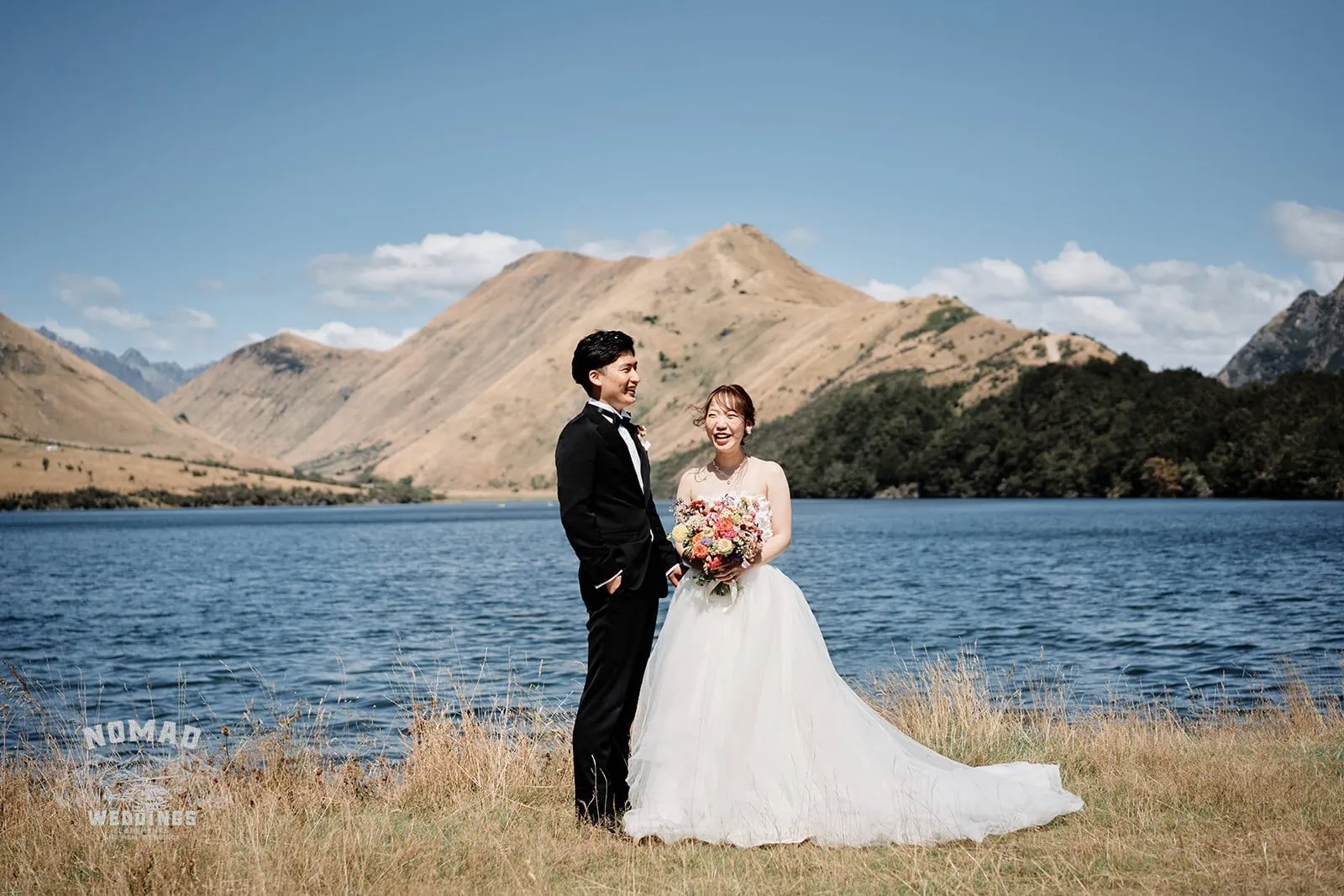 Queenstown New Zealand Elopement Wedding Photographer - A bride and groom standing in front of a lake during the summer season in Queenstown.