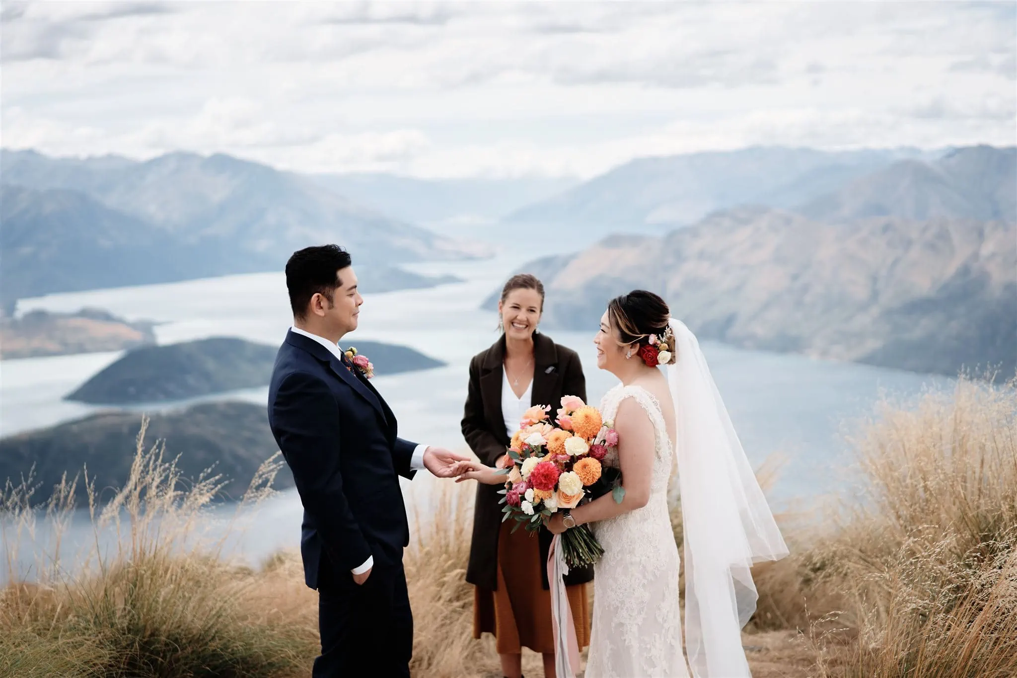 Queenstown New Zealand Elopement Wedding Photographer - The Ultimate Queenstown Elopement Wedding Guide: A bride and groom exchange vows on top of a mountain in New Zealand.