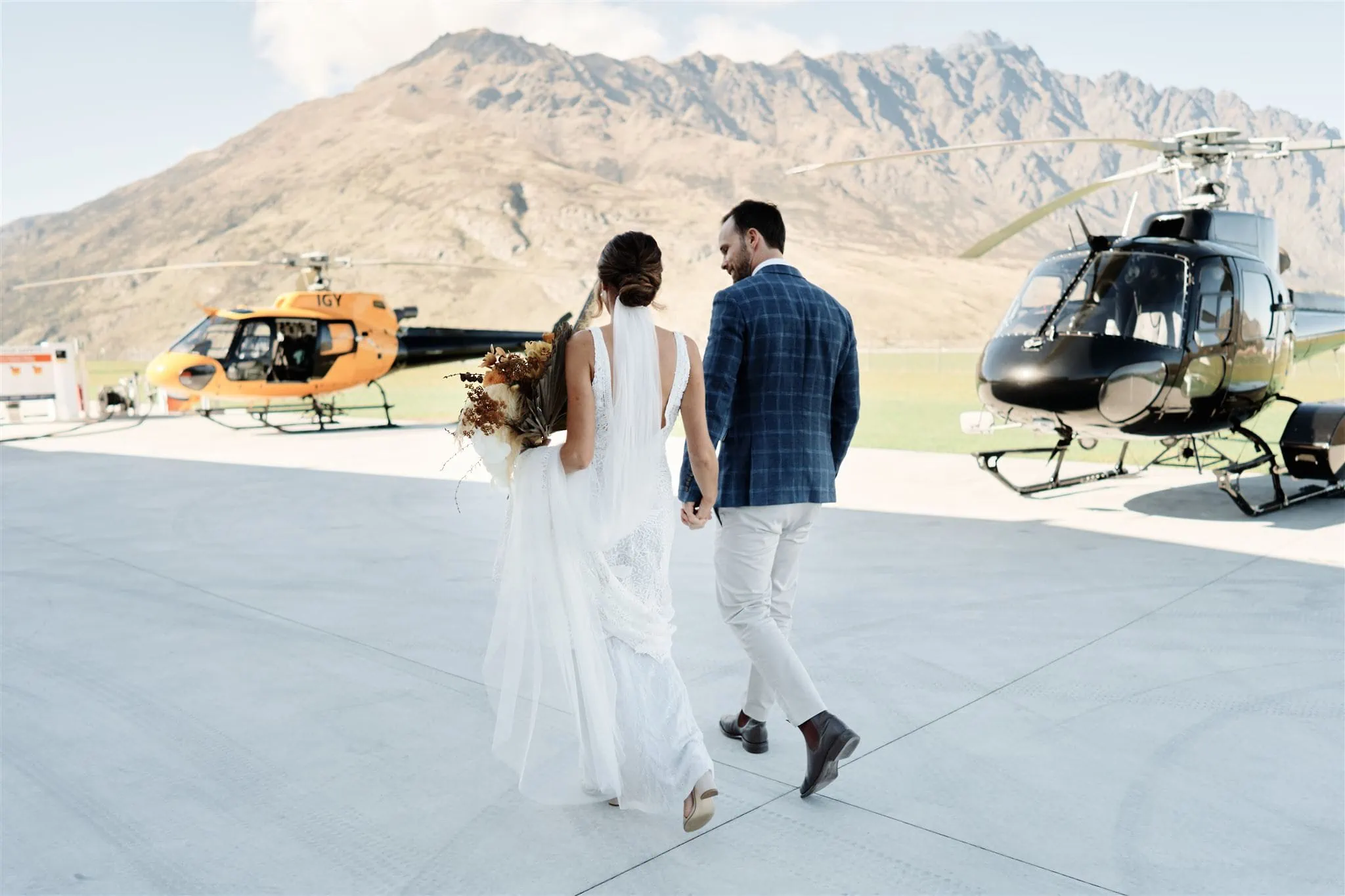 Queenstown New Zealand Elopement Wedding Photographer - The Ultimate Queenstown Elopement Wedding Guide featuring a bride and groom walking towards a helicopter.