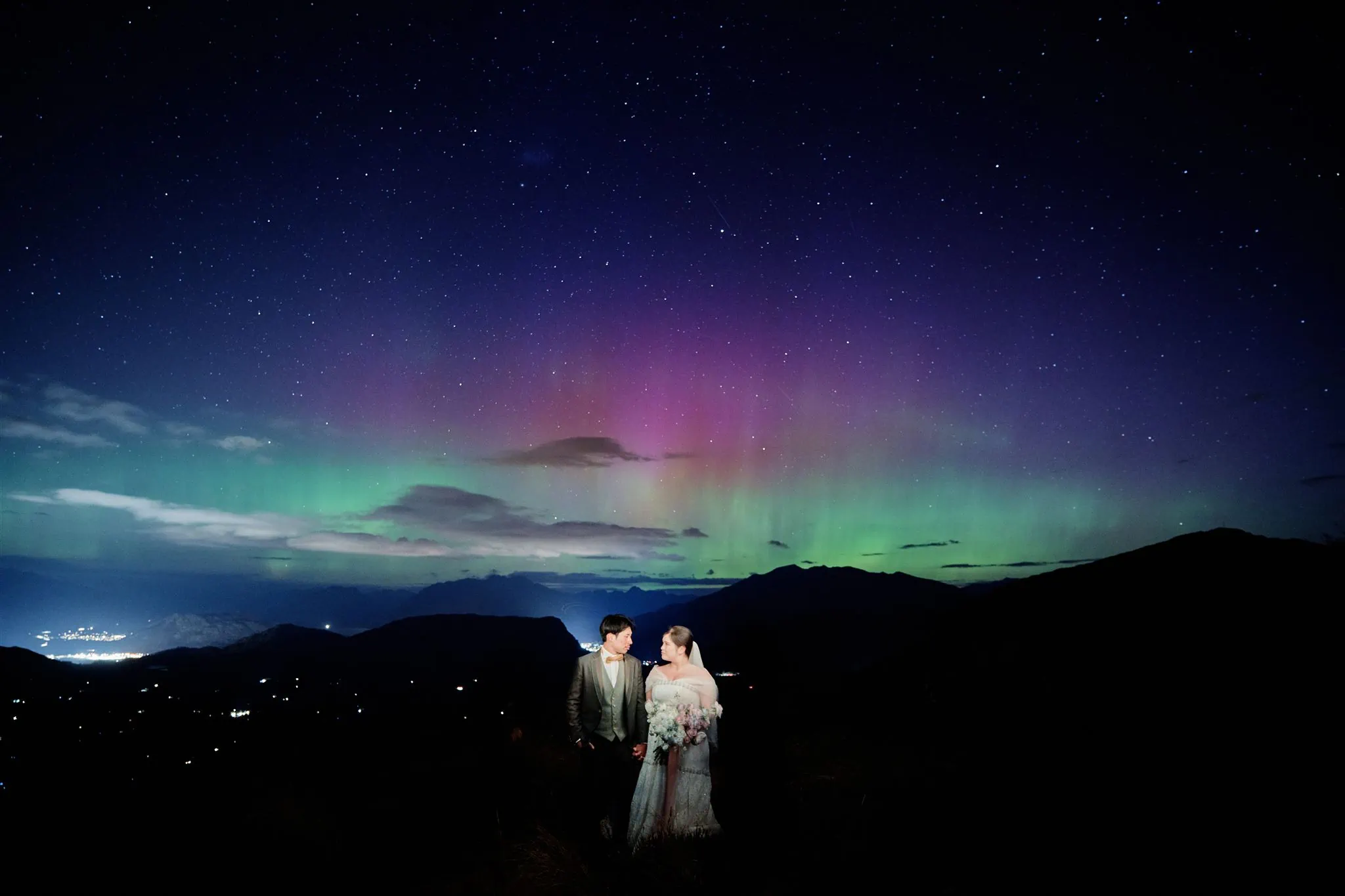 Queenstown New Zealand Elopement Wedding Photographer - A bride and groom standing under the mesmerizing aurora bore, captured in a breathtaking starry night shoot for our portfolio.