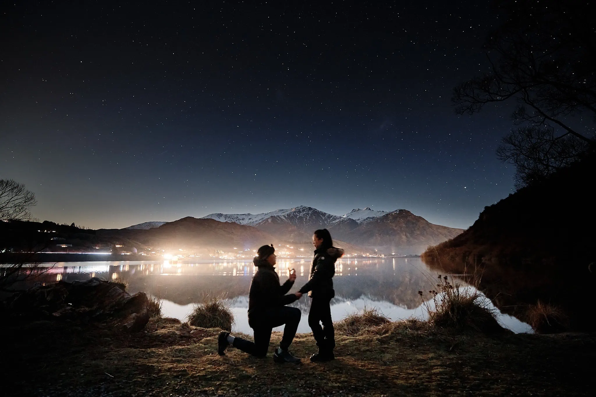 Queenstown New Zealand Elopement Wedding Photographer - A couple kneeling in front of a lake on a starry night.