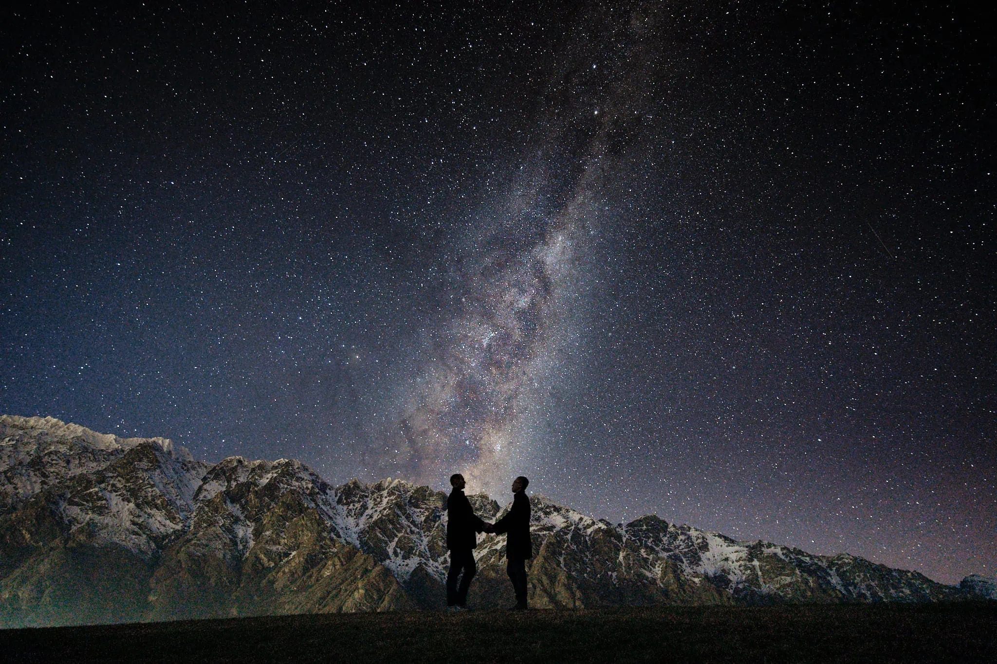 Queenstown New Zealand Elopement Wedding Photographer - Two people standing on top of a hill, admiring the starry night sky.
