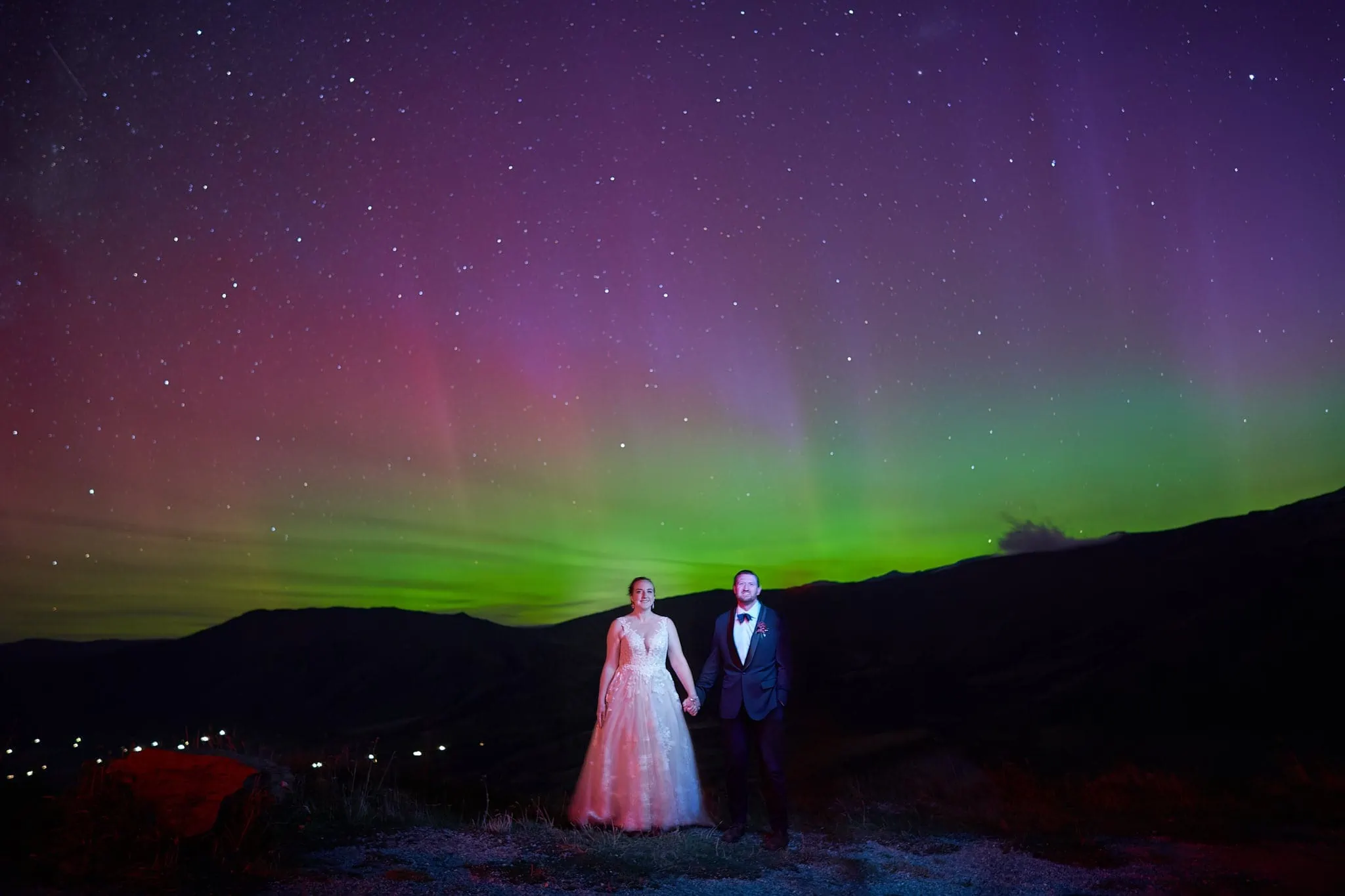 Queenstown New Zealand Elopement Wedding Photographer - A bride and groom standing under the aurora borealis during a Starry Night Shoot.
