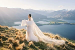Queenstown New Zealand Elopement Wedding Photographer - Josh, a talented photographer, captures a breathtaking bride standing on top of a hill overlooking Lake Wanaka for his portfolio.