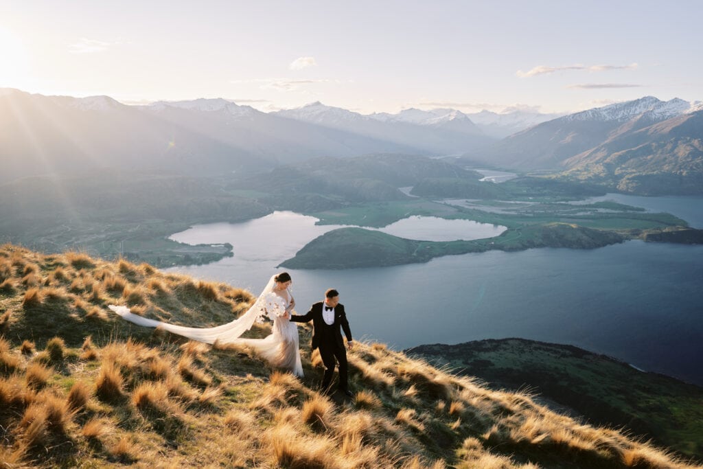 Queenstown New Zealand Elopement Wedding Photographer -         FAQ: Bride and groom standing on top of a hill overlooking lake wanaka.