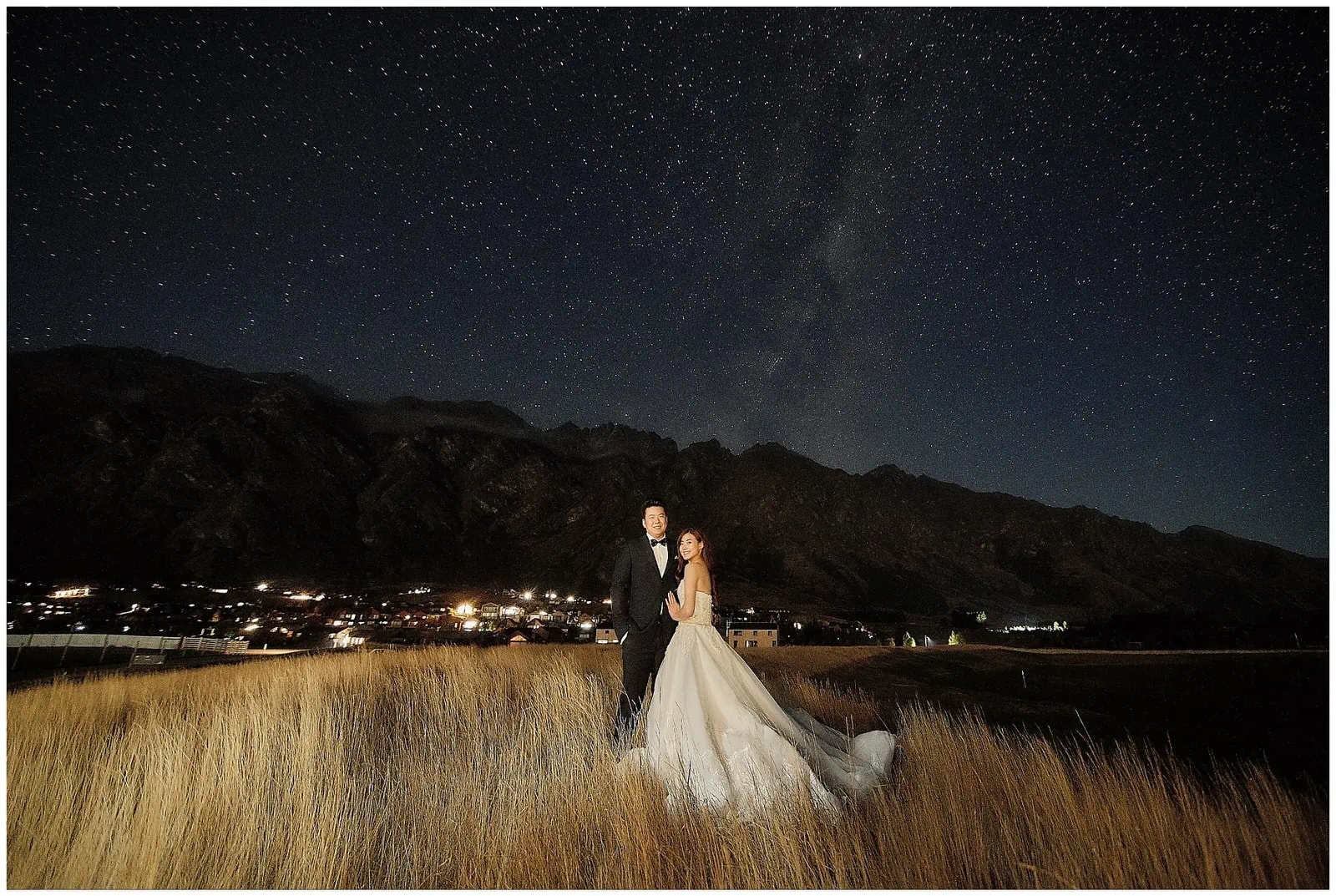 Queenstown New Zealand Elopement Wedding Photographer - A bride and groom standing in a field under the starry night.