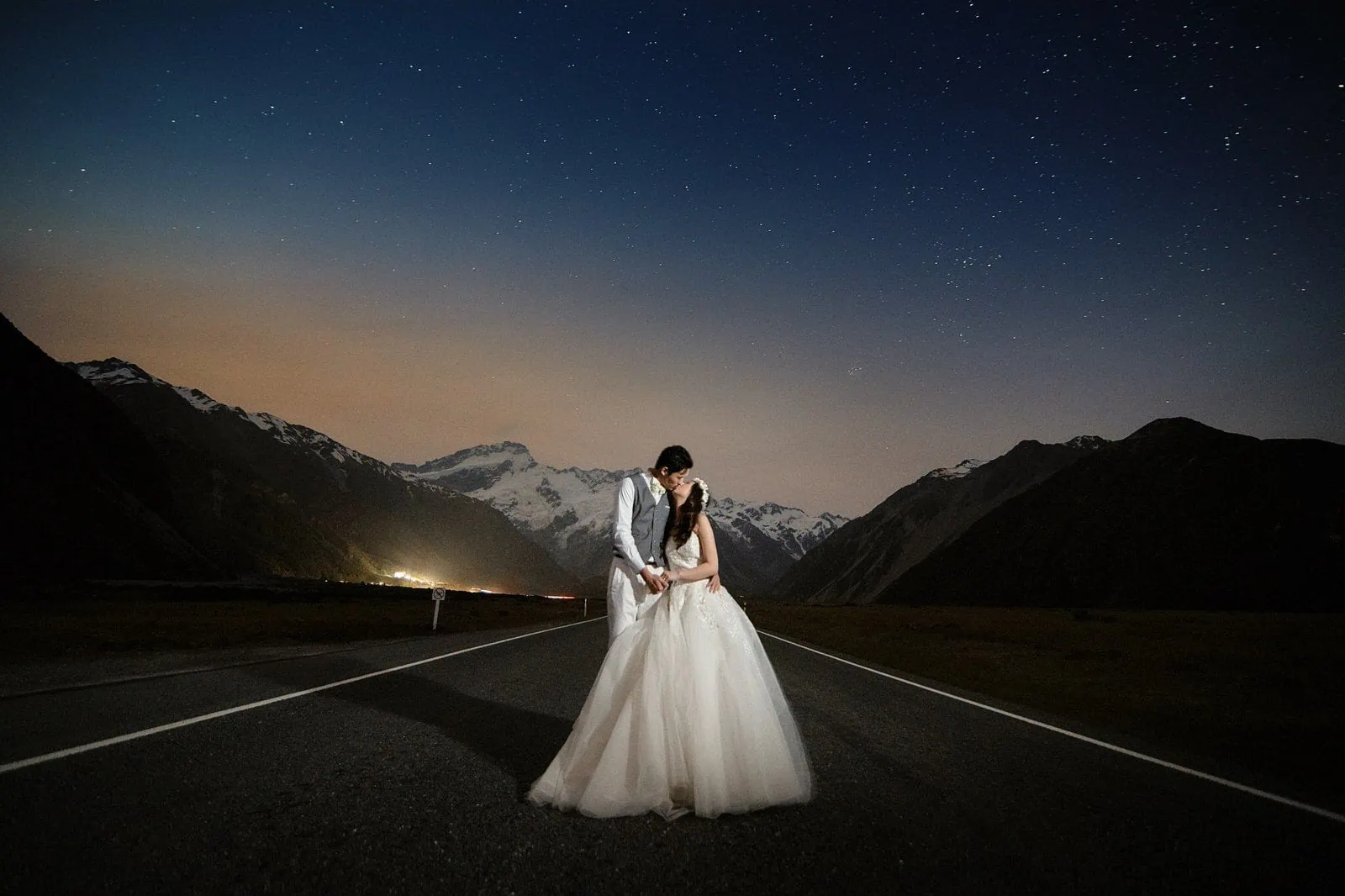 Queenstown New Zealand Elopement Wedding Photographer - A bride and groom standing on a road at night, capturing the ethereal beauty of a starry night.