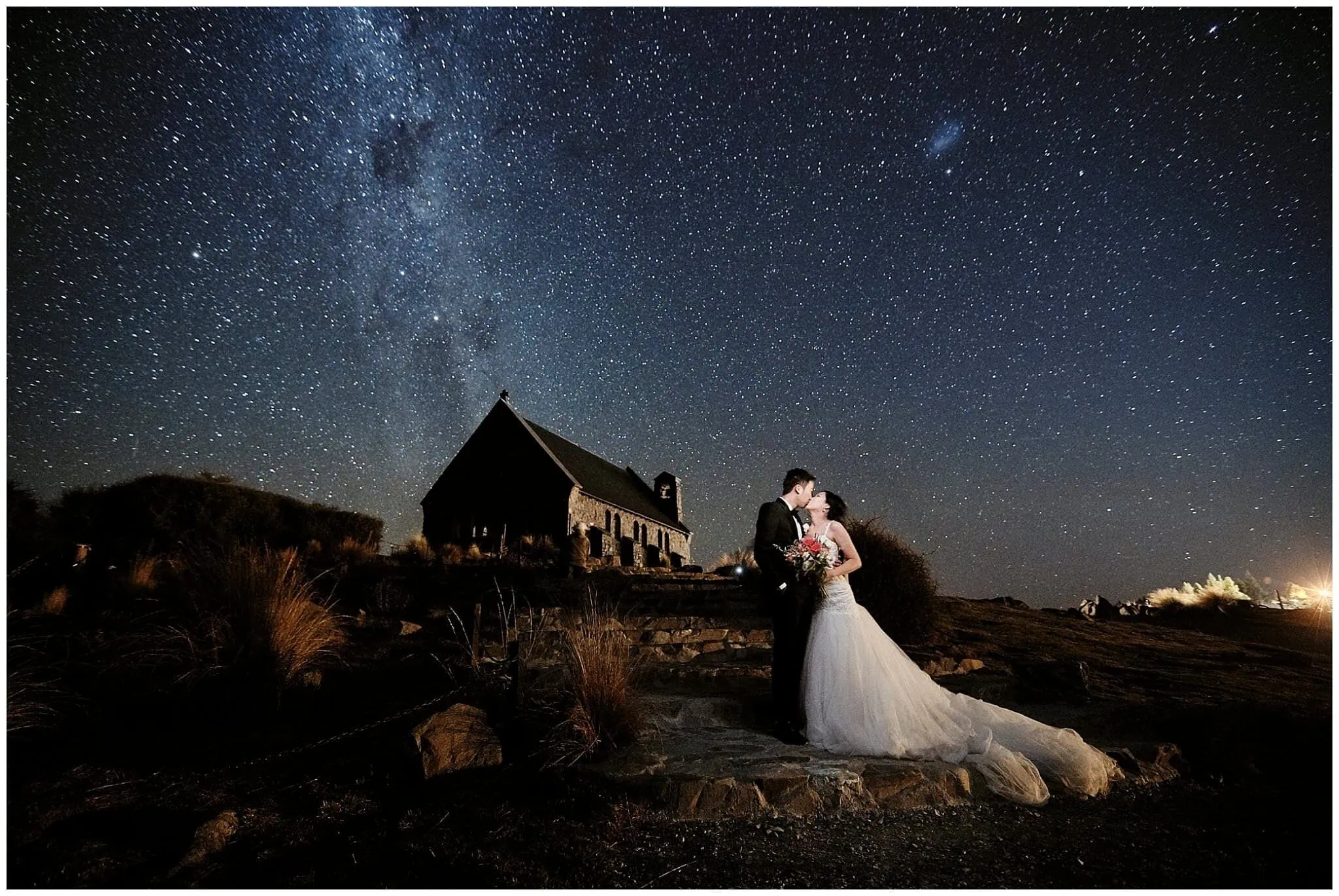 Queenstown New Zealand Elopement Wedding Photographer - A bride and groom standing under the starry milky way in front of a church for their shoot portfolio.