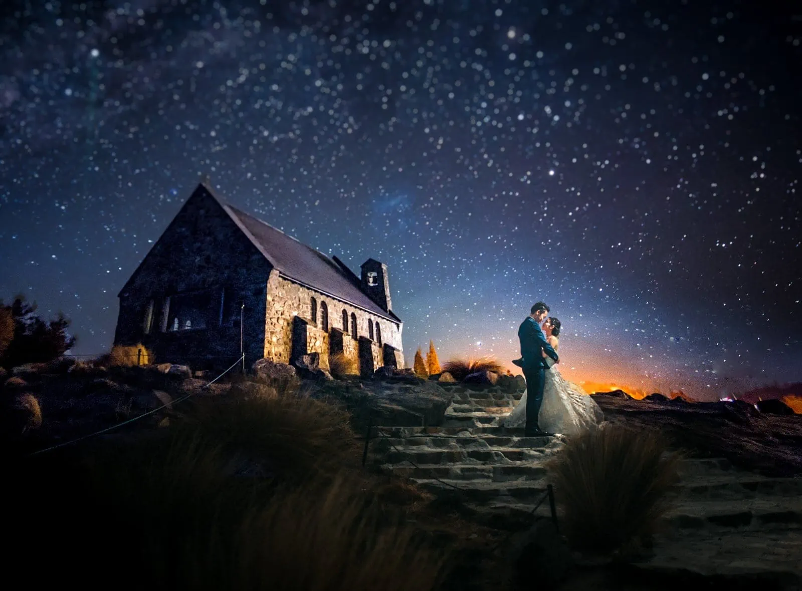 Queenstown New Zealand Elopement Wedding Photographer - A bride and groom pose under the stars in front of a church for their Starry Night shoot.