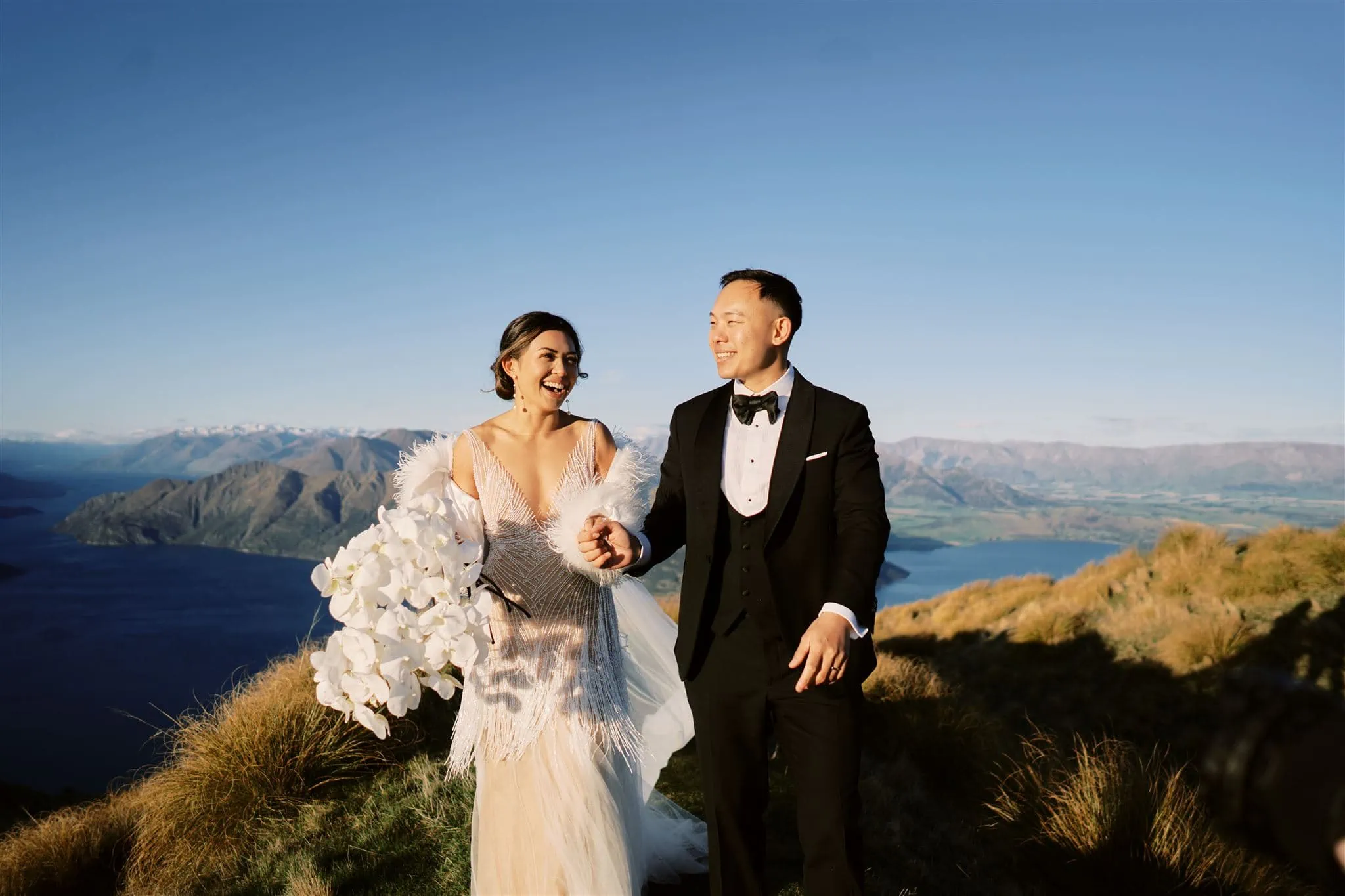 Queenstown New Zealand Elopement Wedding Photographer - A bride and groom enjoying a queenstown heli-wedding package, standing on top of a mountain overlooking Lake Wanaka.