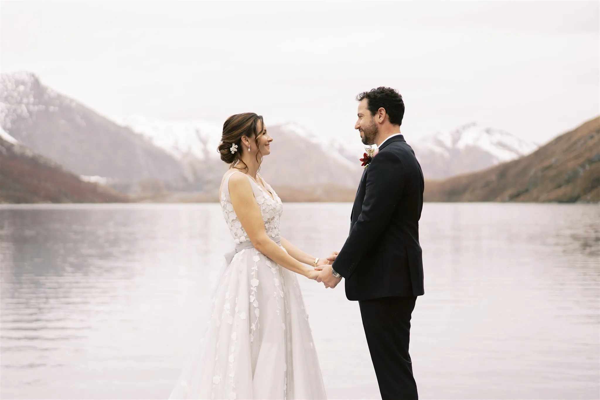 Queenstown New Zealand Elopement Wedding Photographer - Alex & Shahar, a bride and groom, captured their special Queenstown elopement moment in front of a serene lake surrounded by majestic mountains.