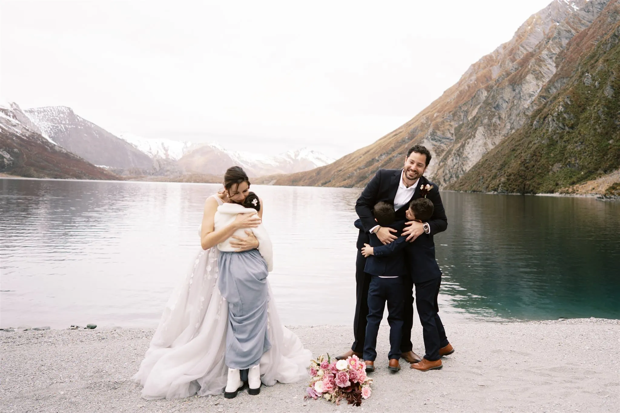 Queenstown New Zealand Elopement Wedding Photographer - A bride and groom hugging on the shore of Lake Wakatipu in Queenstown, New Zealand.