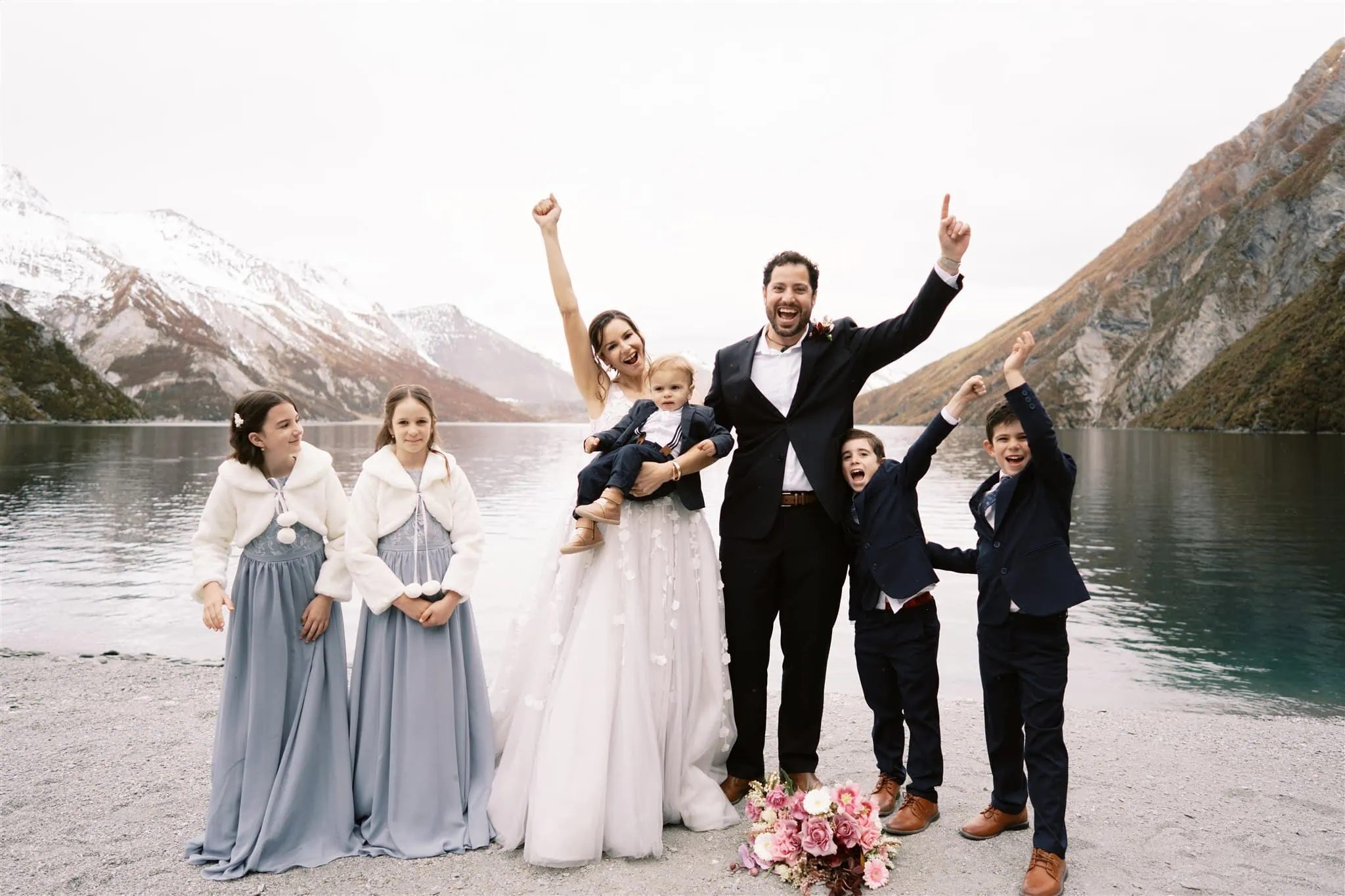 Queenstown New Zealand Elopement Wedding Photographer - A wedding party with their arms raised in the air, stargazing in front of a lake.