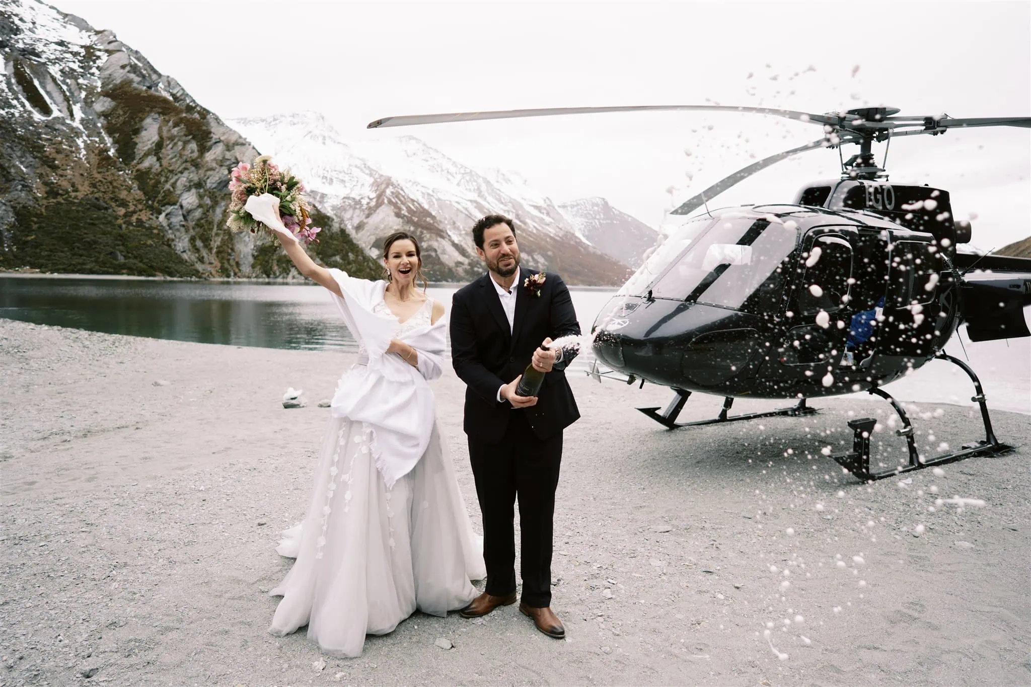Queenstown New Zealand Elopement Wedding Photographer - Alex & Shahar's Queenstown elopement captures them in a romantic moment, standing together in front of a helicopter.