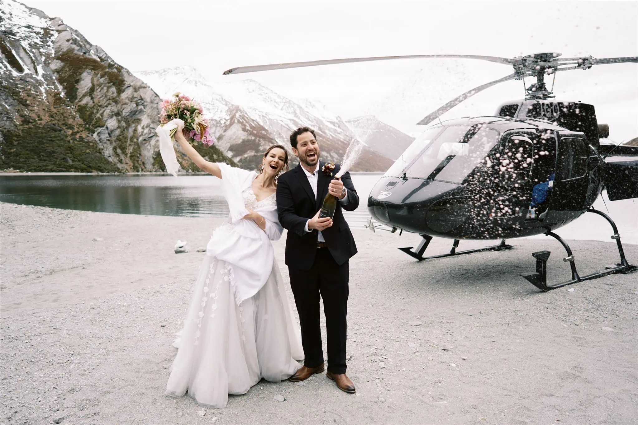 Queenstown New Zealand Elopement Wedding Photographer - Alex & Shahar, a bride and groom, pose in front of a helicopter during their Queenstown elopement.
