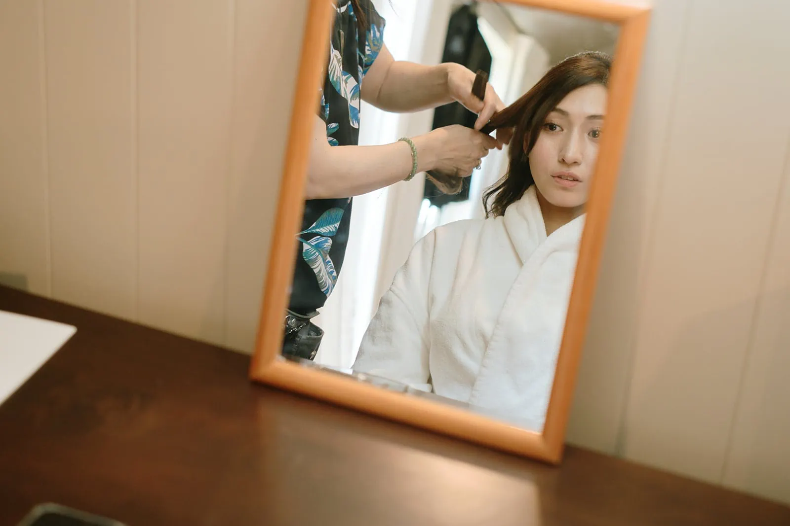 Queenstown Tekapo New Zealand Heli Wedding Elopement Pre-Wedding Shoot Photographer クイーンズタウン　テカポ　ニュージーランド　エロープメント 前撮り　フォトウェディング　結婚式 | A woman getting her hair styled for her pre-wedding shoot as reflected in a mirror.