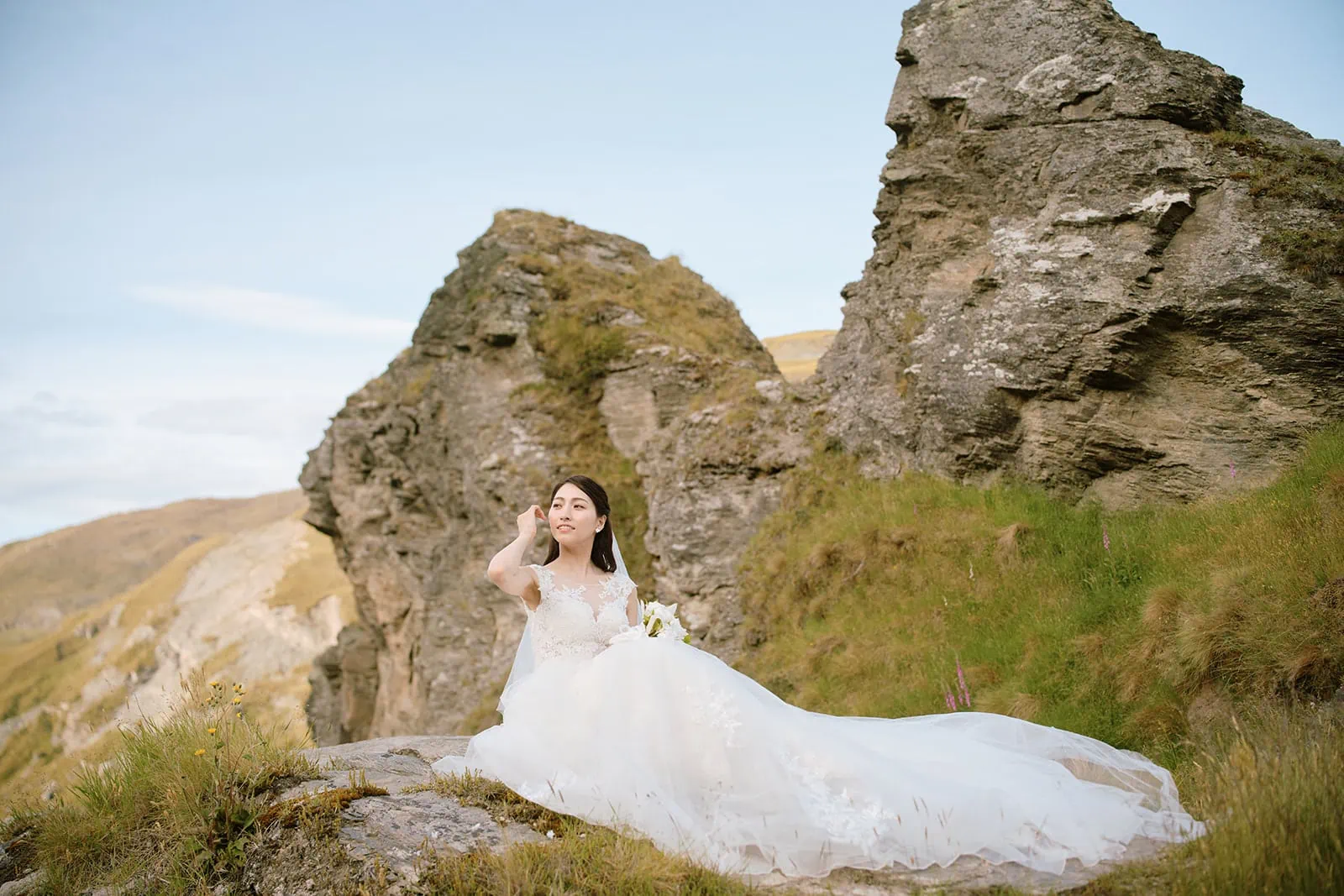 Queenstown Elopement Heli Wedding Photographer クイーンズタウン結婚式 | A woman in a wedding dress sitting on top of a rock during her pre-wedding shoot.
