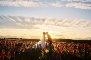 Queenstown New Zealand Elopement Wedding Photographer - Tomomi's portfolio showcases a bride and groom kissing in a field of flowers at sunset.