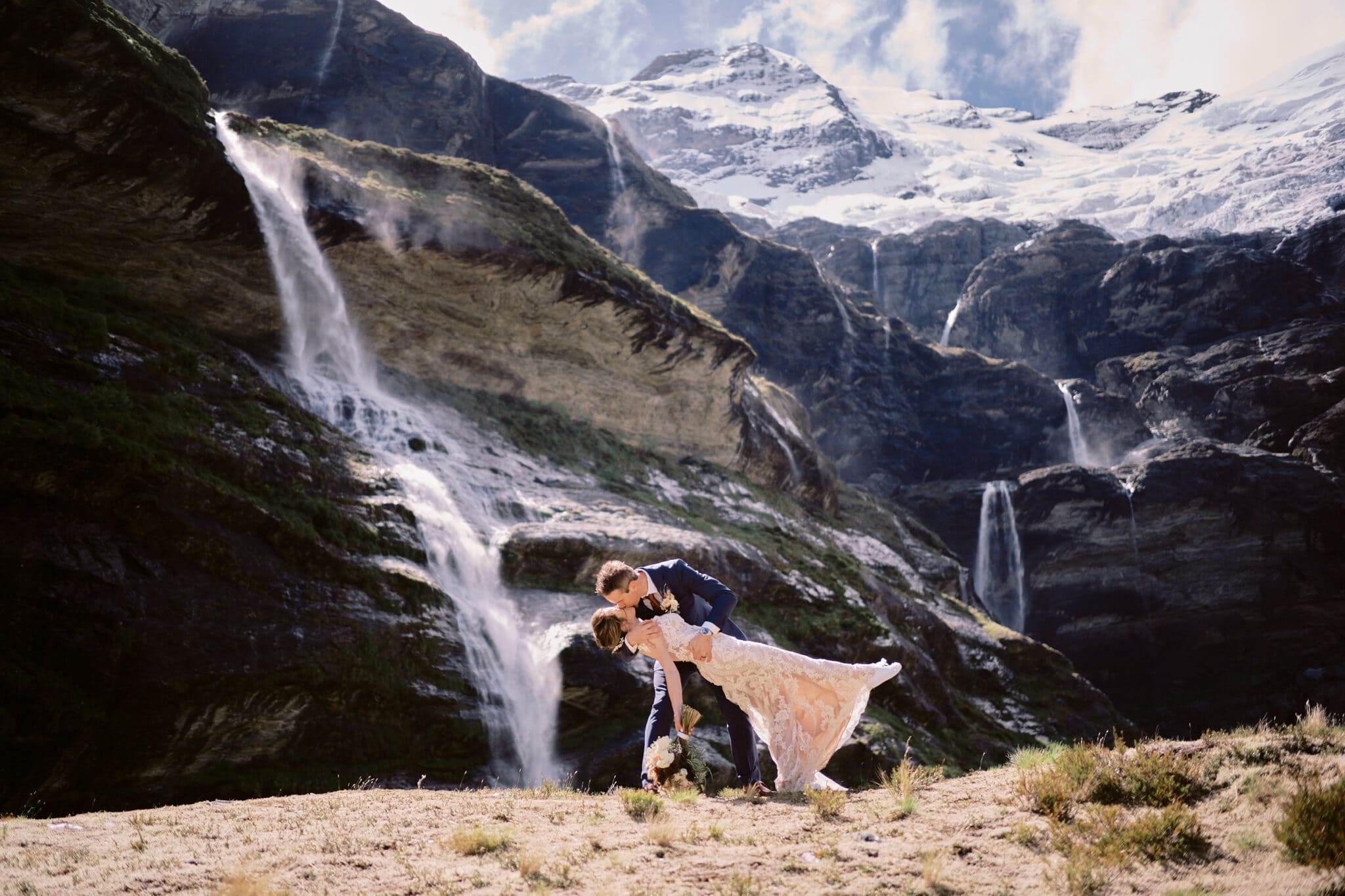 Queenstown New Zealand Elopement Wedding Photographer - A bride and groom sharing an intimate kiss in front of a picturesque waterfall.