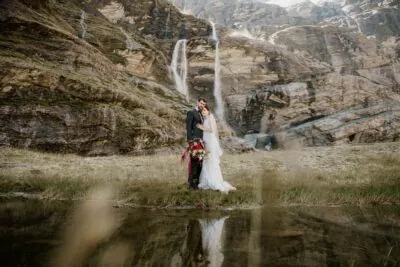 Queenstown New Zealand Elopement Wedding Photographer - A stunning bride and groom standing in front of the breathtaking Earnslaw Burn waterfall.