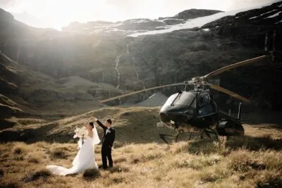 Queenstown New Zealand Elopement Wedding Photographer - A bride and groom standing in front of a helicopter at Earnslaw Burn.
