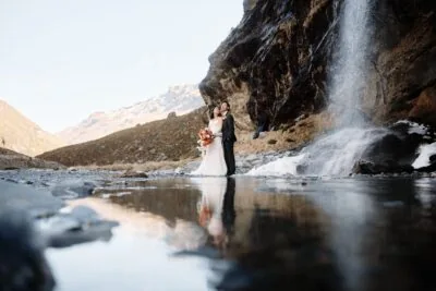 Queenstown New Zealand Elopement Wedding Photographer - A bride and groom standing in front of the Earnslaw Burn waterfall.