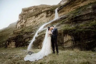 Queenstown New Zealand Elopement Wedding Photographer - A bride and groom standing in front of the stunning Earnslaw Burn waterfall.