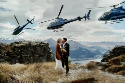 Queenstown New Zealand Elopement Wedding Photographer - A bride and groom standing on top of Cecil Peak, with helicopters in the background.