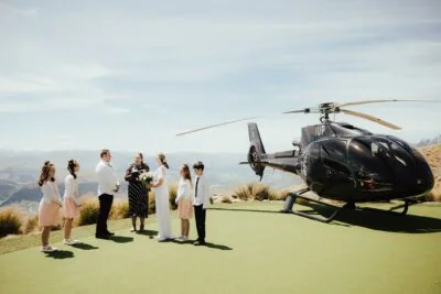 Queenstown New Zealand Elopement Wedding Photographer - A wedding party is standing next to a helicopter on Cecil Peak.