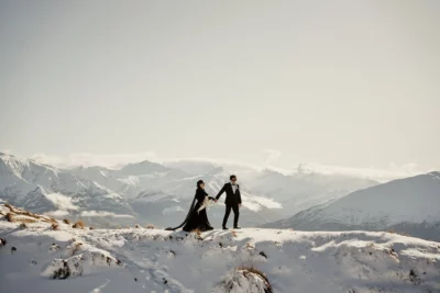 Queenstown New Zealand Elopement Wedding Photographer - A bride and groom standing on top of Coromandel Peak, a snow-covered mountain.